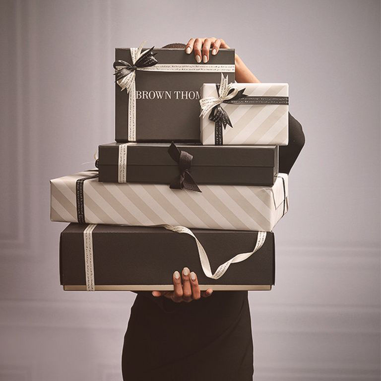 Person holding a stack of gift-wrapped boxes with bows.
