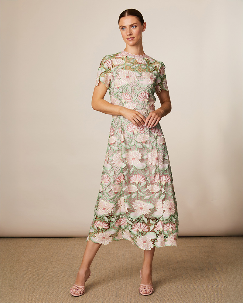 Woman in a floral midi dress poses against a neutral background.