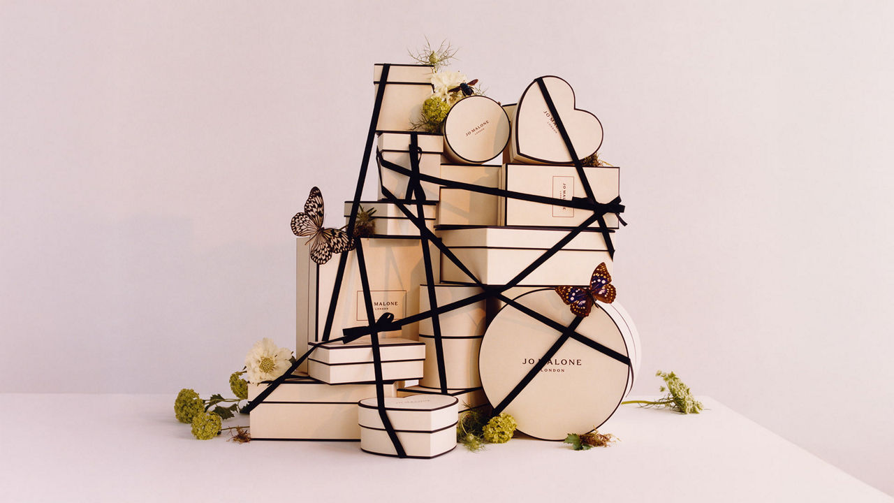 Stacked gift boxes with black ribbons, adorned with butterflies and flowers.