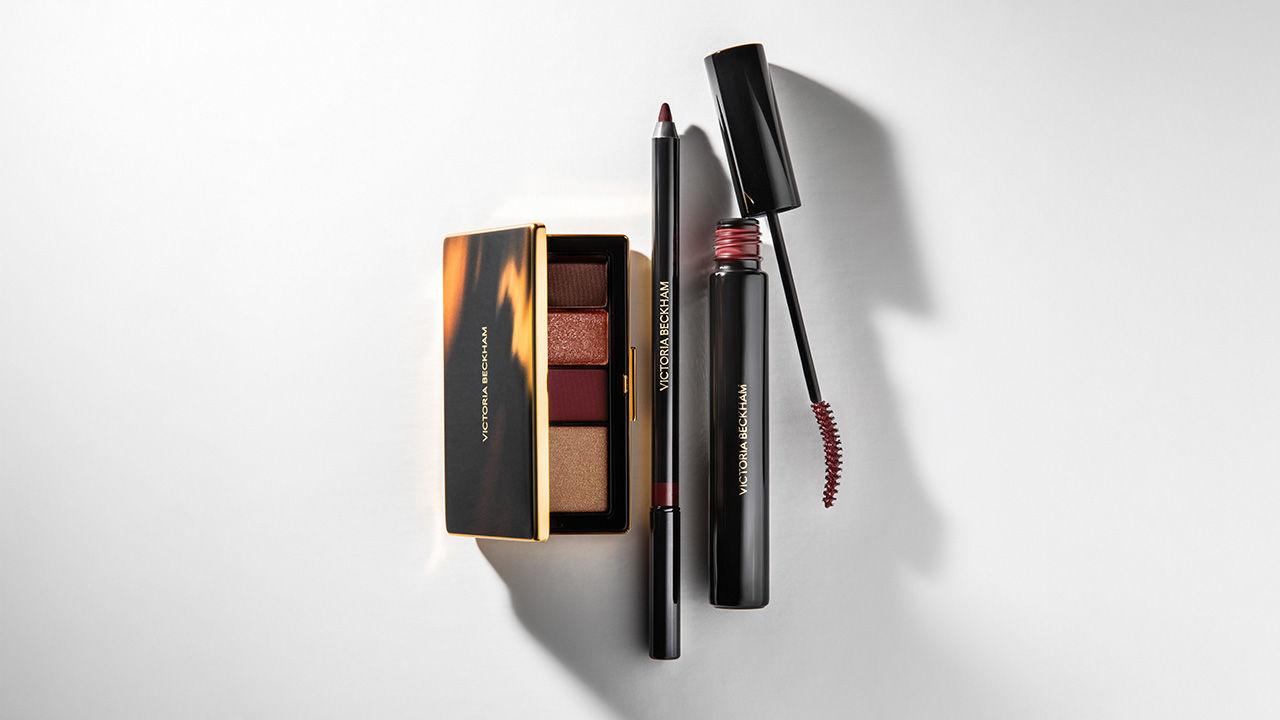 Victoria Beckham Beauty products: eyeshadow palette, lip liner, and mascara, displayed on a light surface.