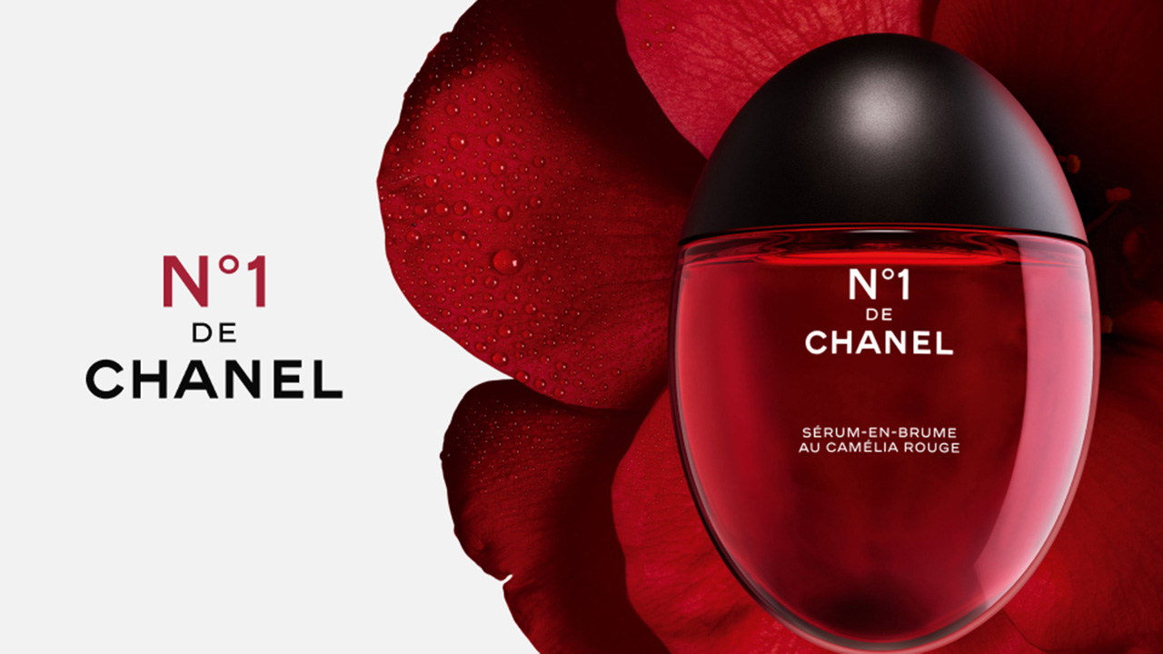 No.1 De Chanel fragrance bottle in front of a red flower