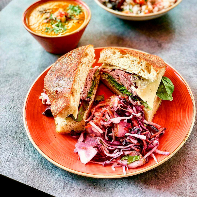 Bowls of salads with leafy greens, sliced radishes, almonds, and various toppings on a green surface.