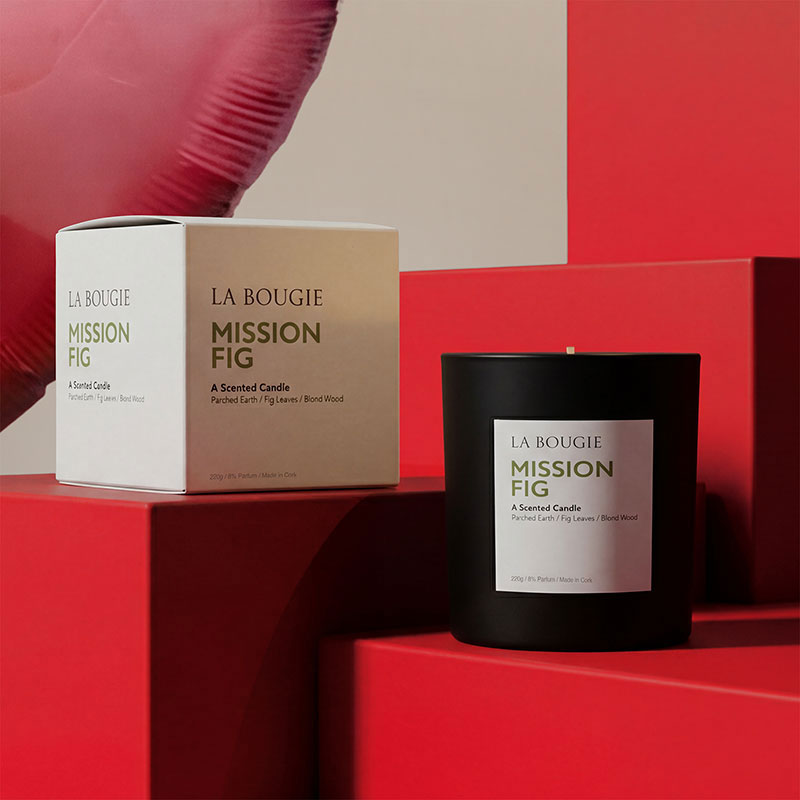 Scented candle with box on red steps, heart-shaped balloon in the background.