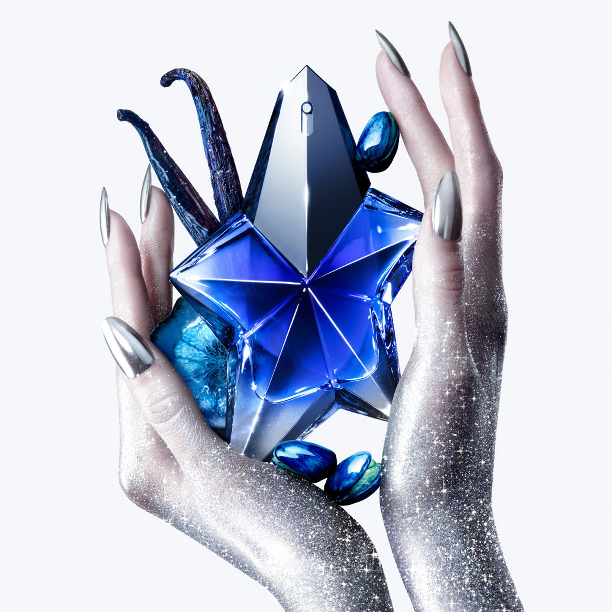 MUGLER Angel Stellar Eau de Parfum 100ml, deep blue star-shaped bottle with silver facets, held in glittering hands with vanilla pod detail