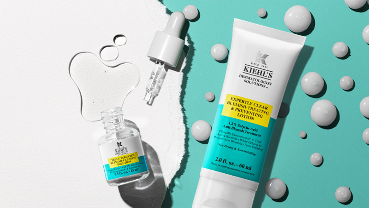 Kiehl's skincare products, including a dropper bottle and tube, with liquid droplets on a split white and teal background.

