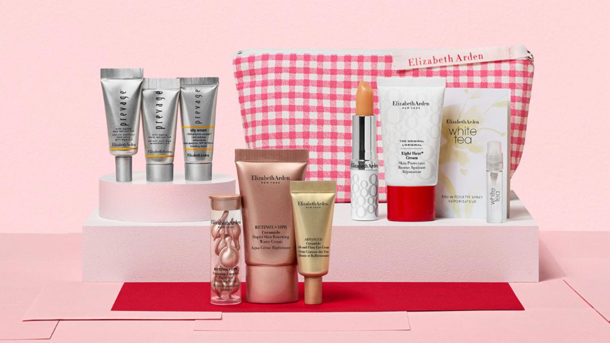 Elizabeth Arden skincare and fragrance gift set with pink checkered pouch, serums, creams and lipstick on pink background