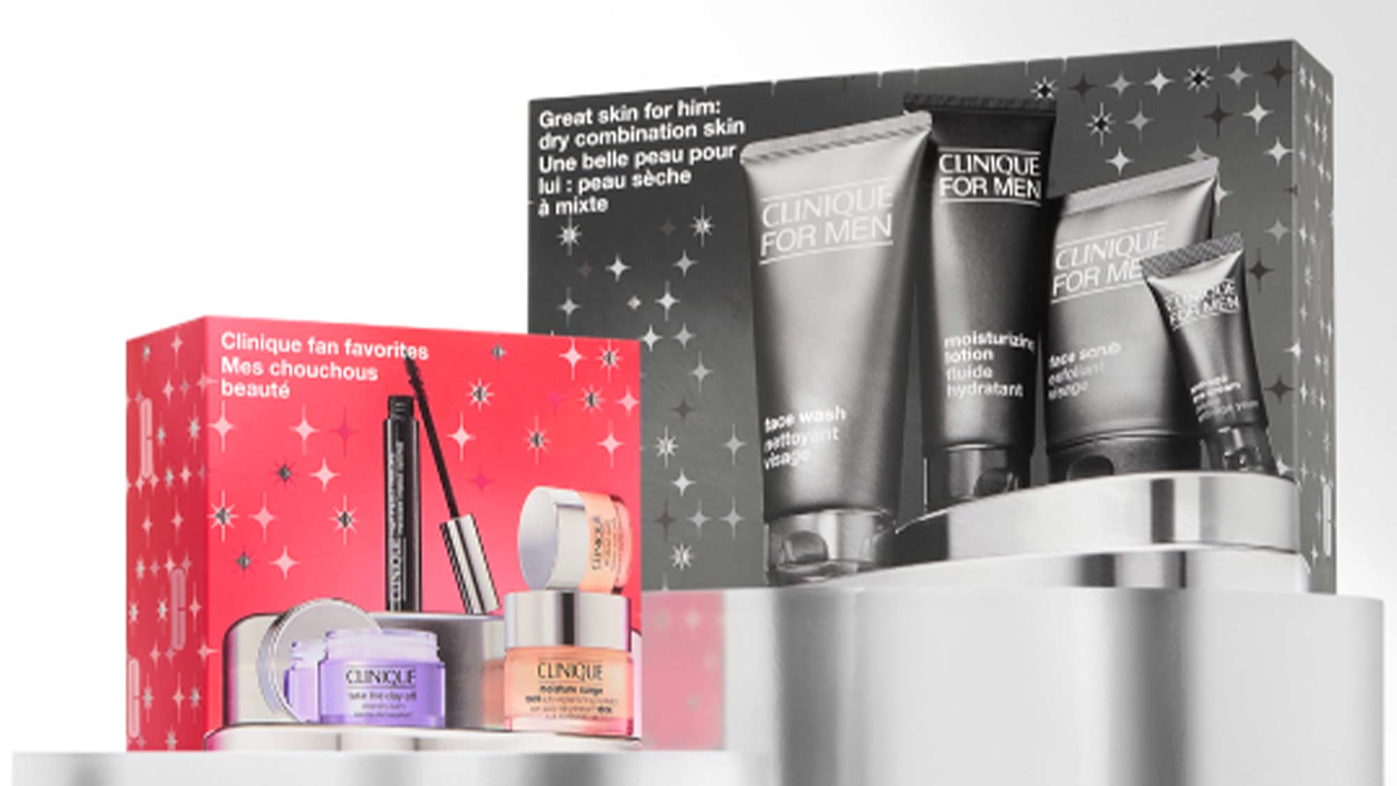 Two Clinique gift sets on a display: one for women in a red box, and one for men in a black box, both showcasing skincare products.