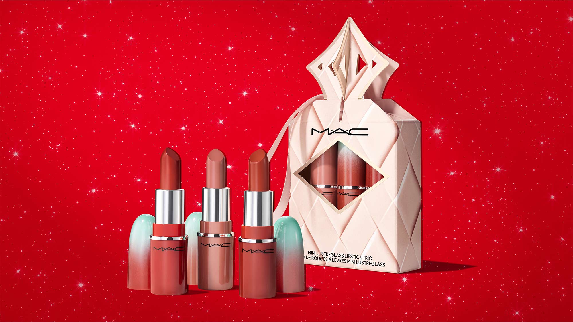 Three MAC lipsticks with a decorative gift box on a red, sparkly background.