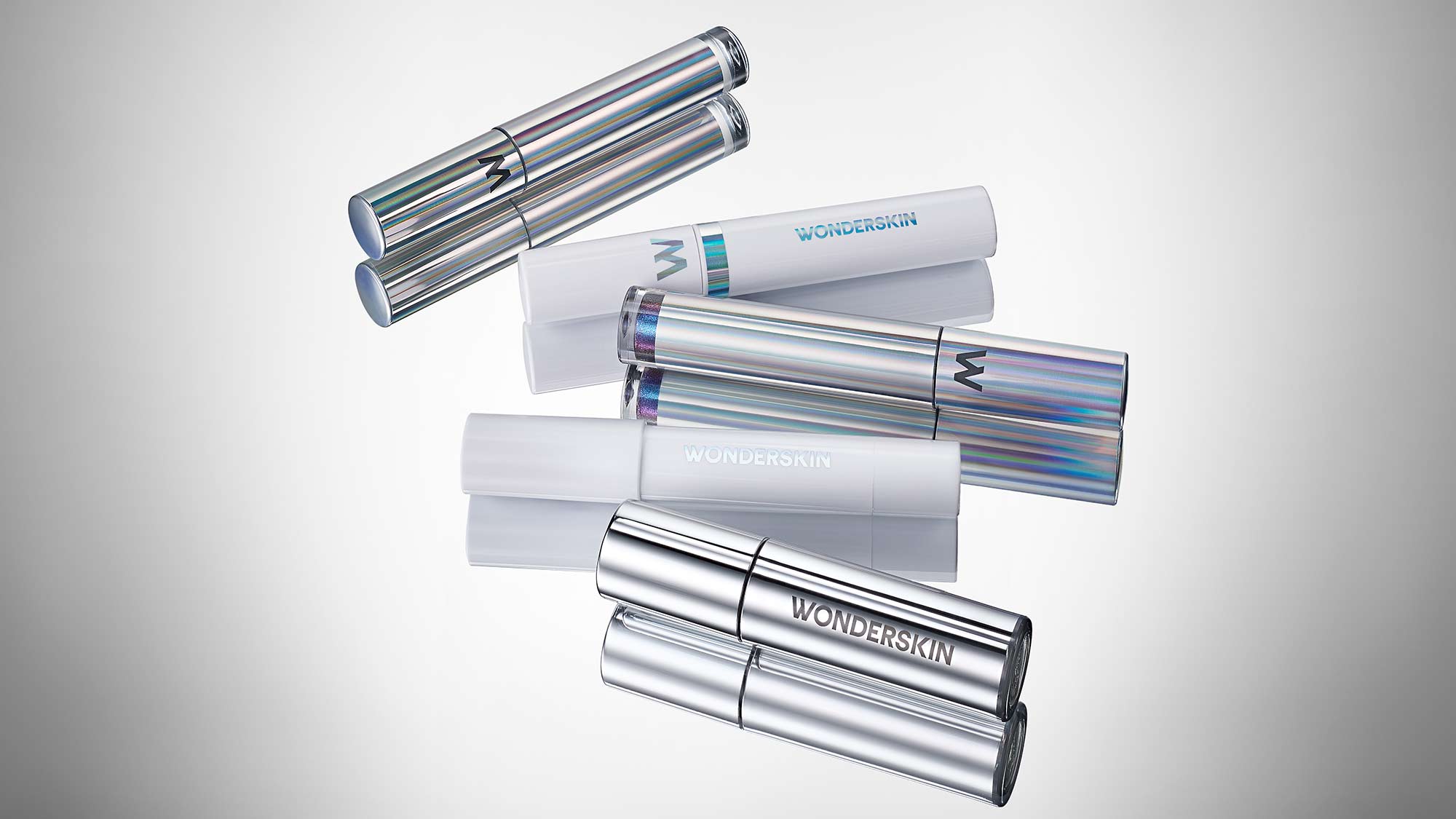 Several iridescent and metallic cylindrical cosmetic containers with 'Wonderskin' branding.