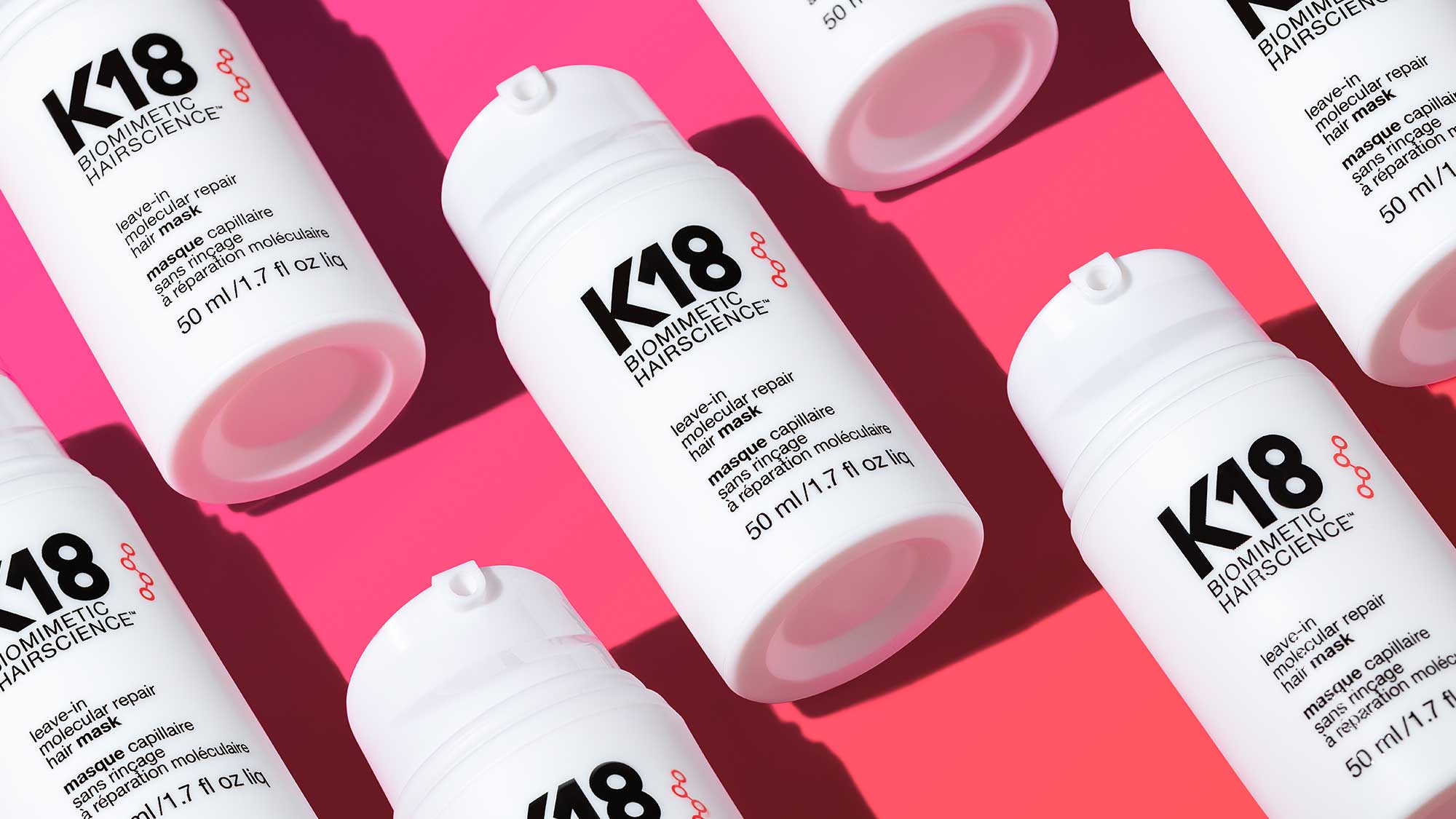 K18 hair mask bottles on pink background.