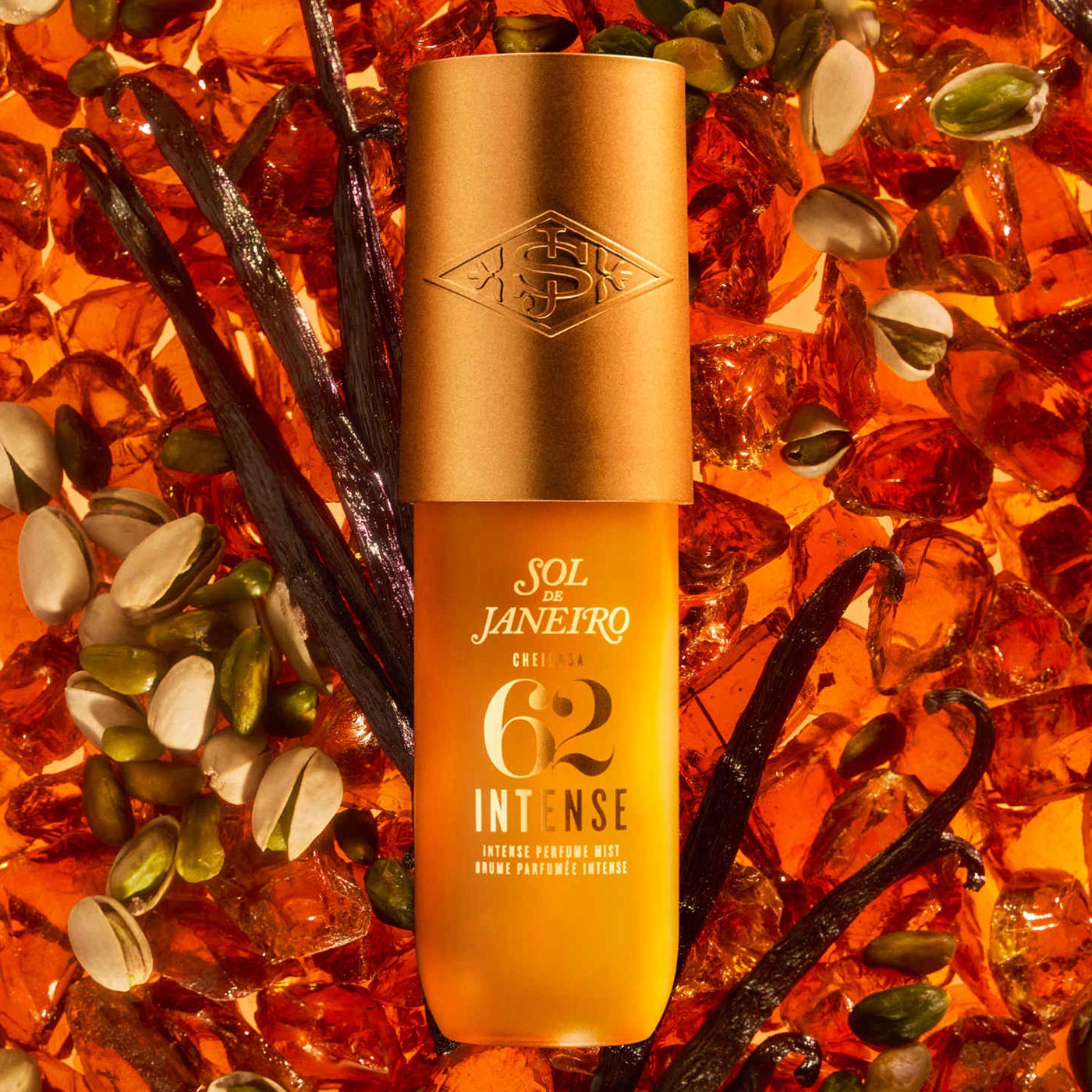 Sol de Janeiro Cheirosa 62 Intense perfume mist bottle surrounded by amber glass beads, vanilla pods, and pistachios on warm orange background