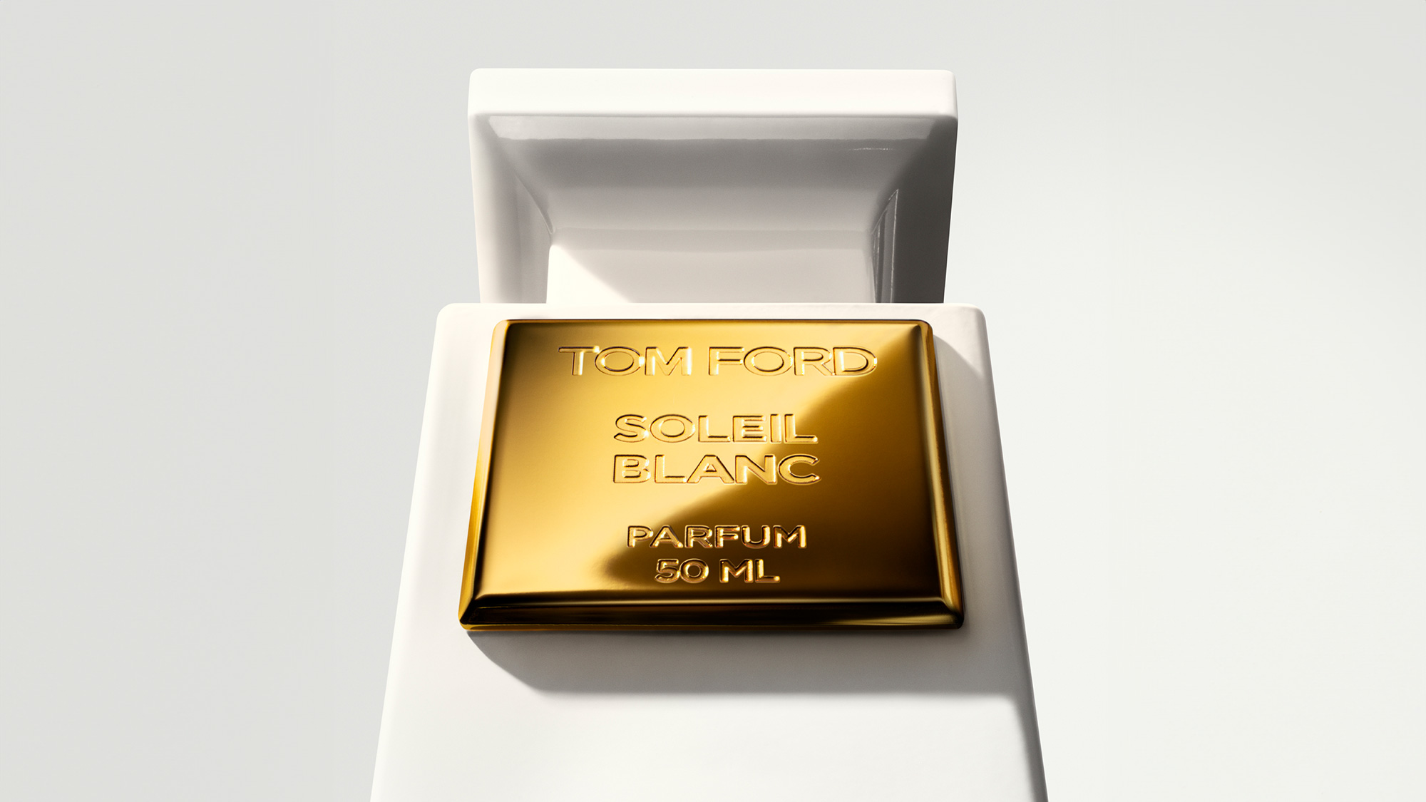 Tom Ford Soleil Blanc Parfum 50ml bottle in gold finish presented on white cubic stand