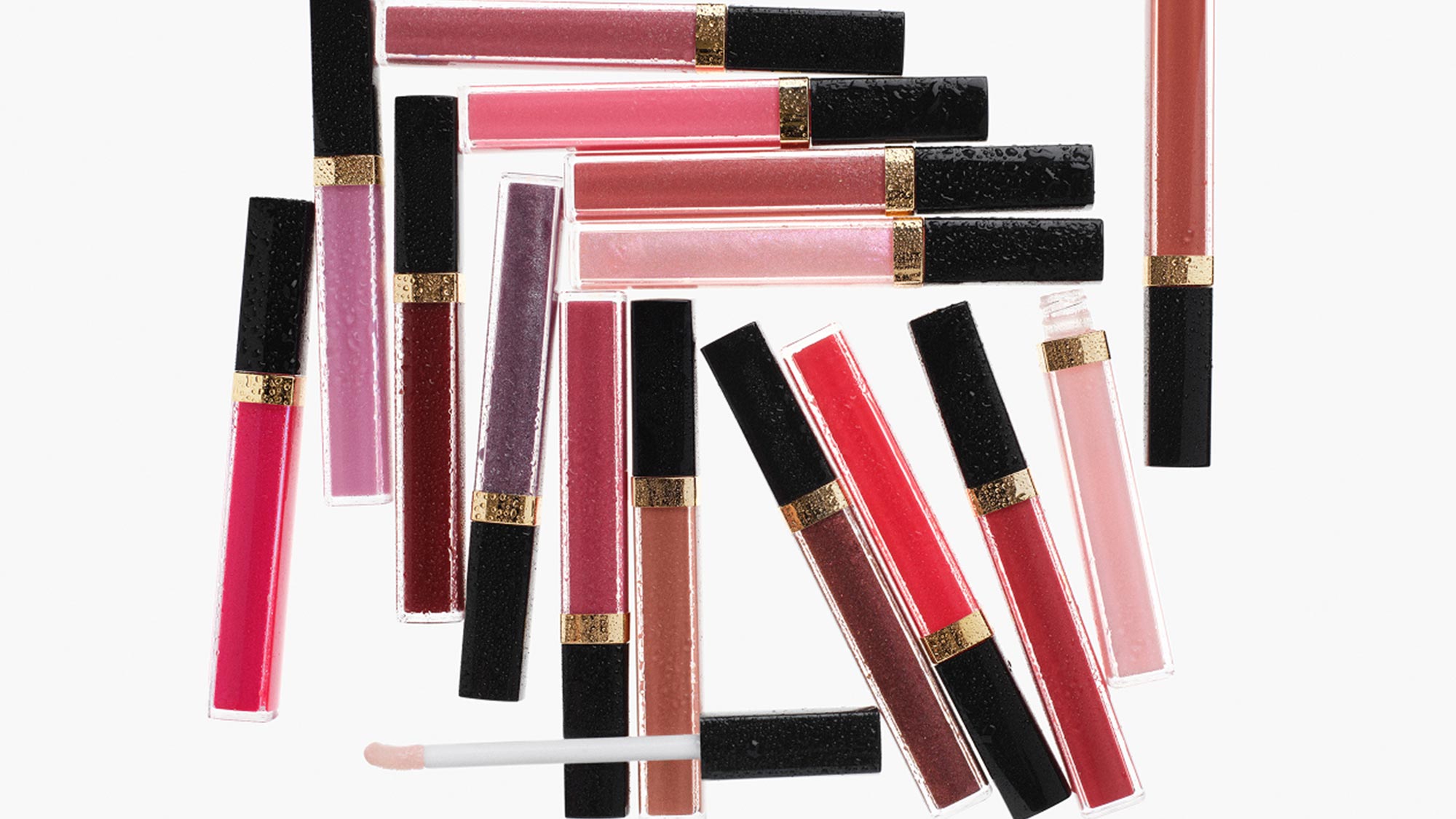 Assortment of Rouge Coco Hydra Gloss lip products in various shades with black caps and gold accents, arranged on white background