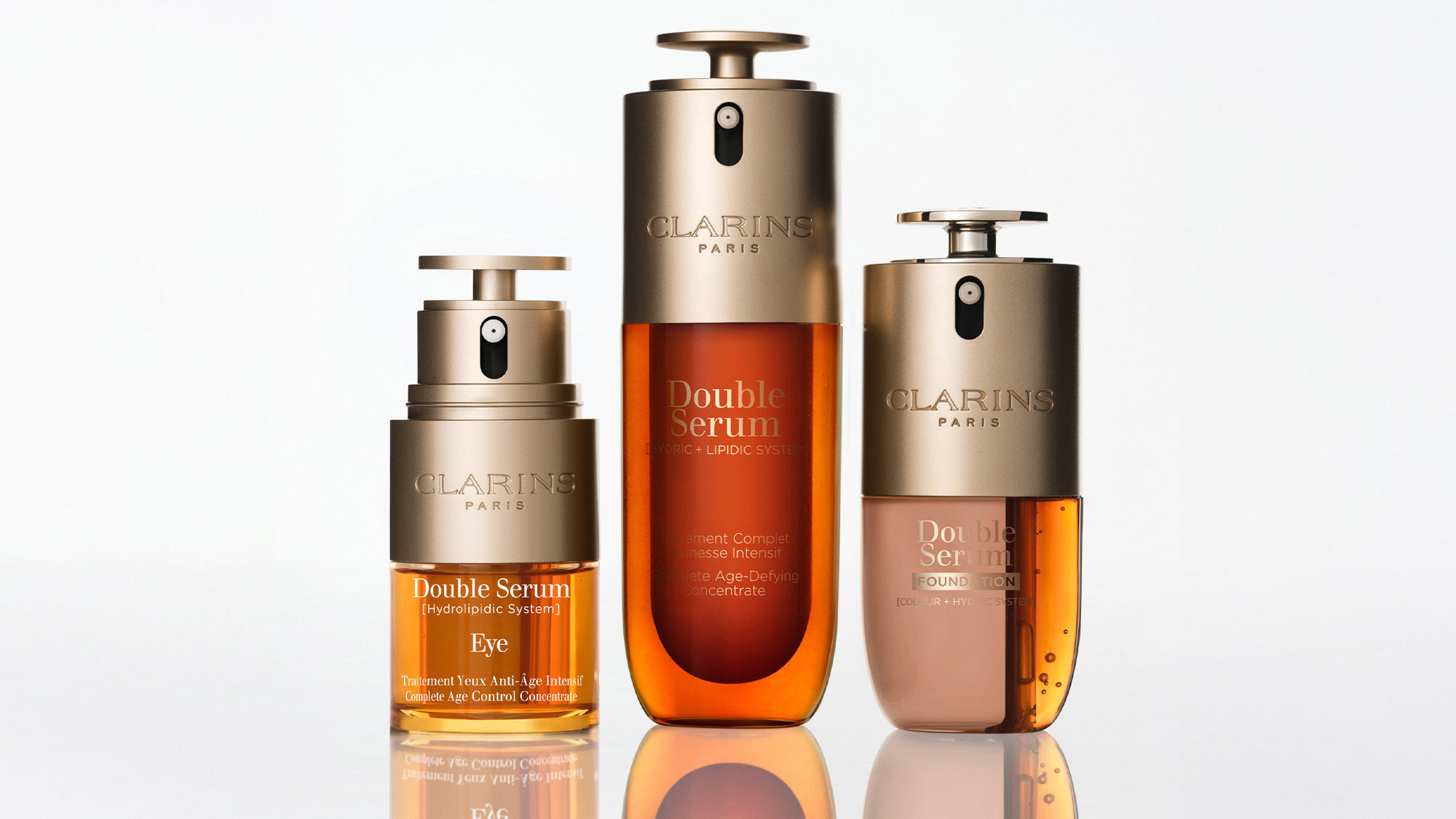 Three Clarins Double Serum bottles in various sizes with golden and amber liquid formulas