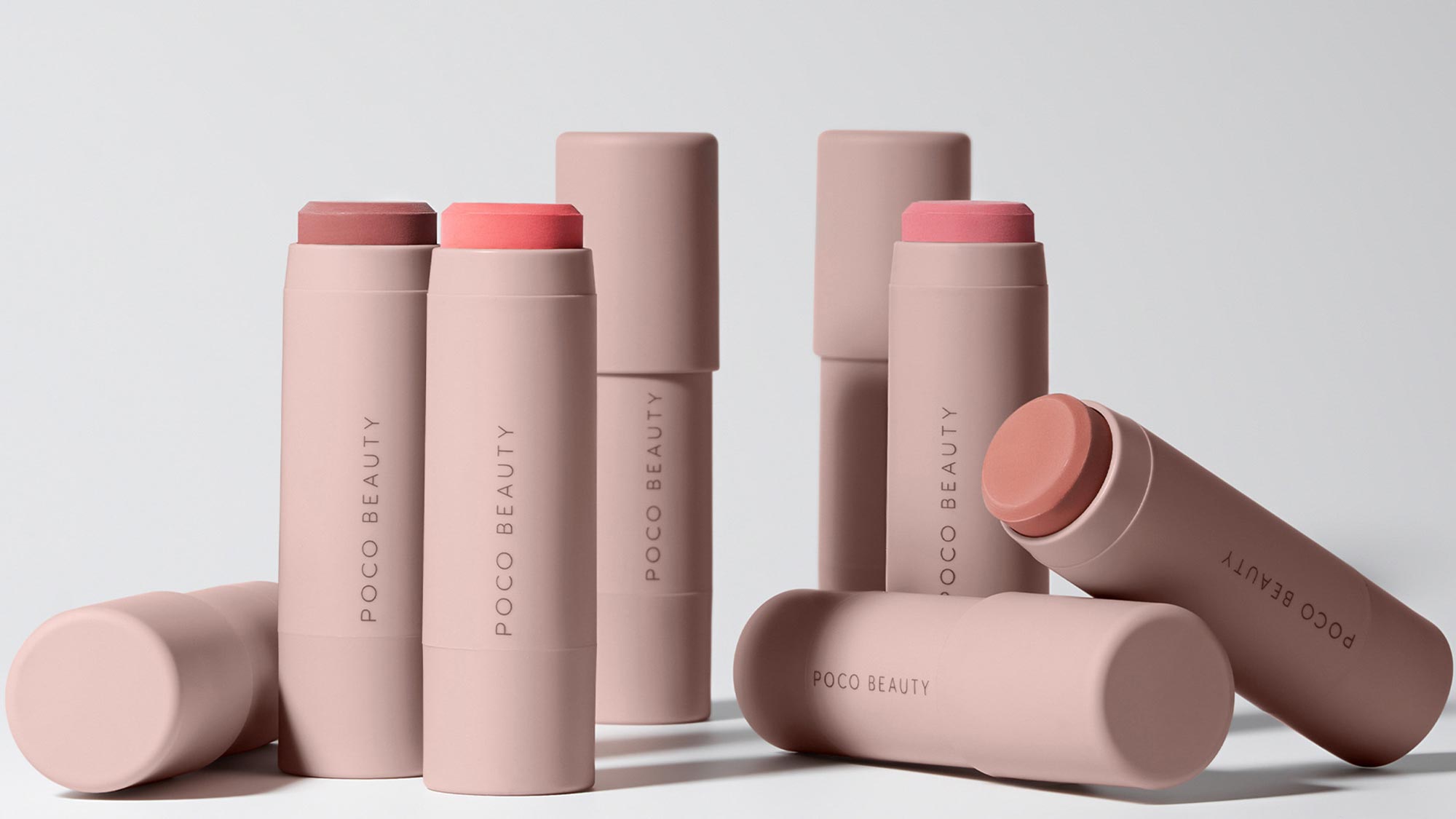 Collection of POCO Beauty cream stick products in pink and nude tones with coloured caps