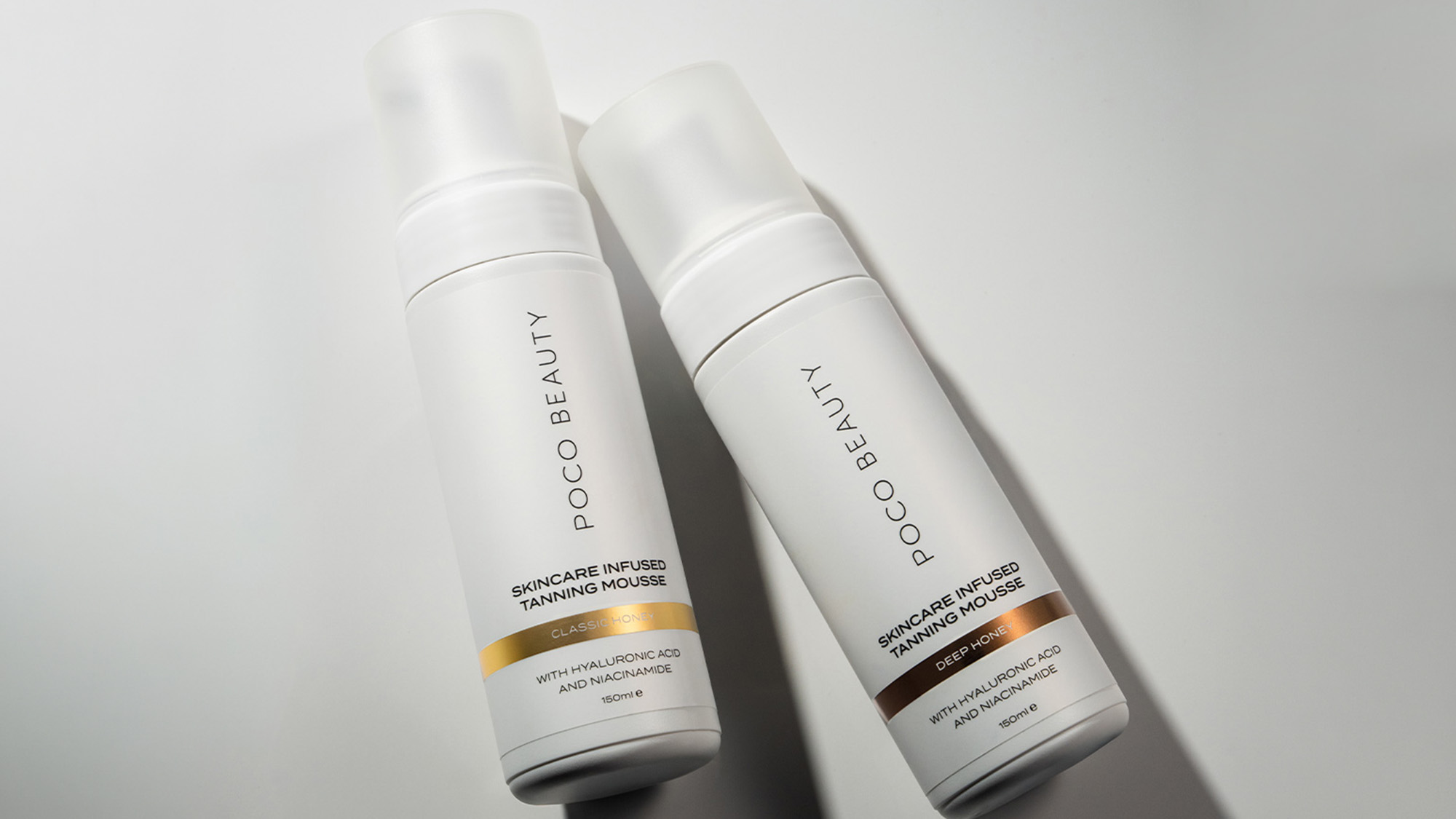 Two white pump bottles of Poco Beauty skincare infused tanning mousse with gold and bronze accent bands