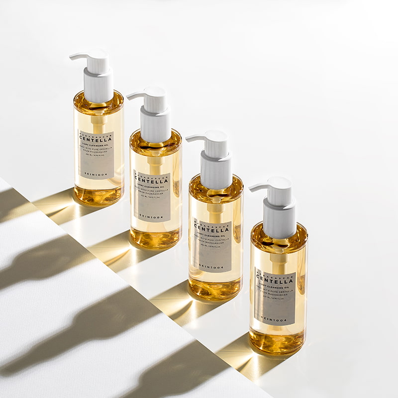 Four amber-colored pump bottles with white labels and caps, casting shadows on a white surface.