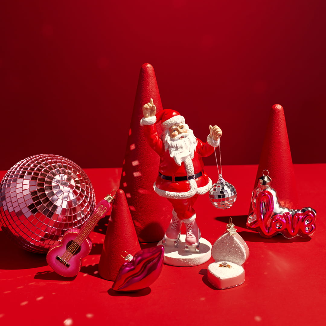 Santa figurine with disco ball, red cones, a silver disco ball, pink guitar, and decorative lips on a red background.
