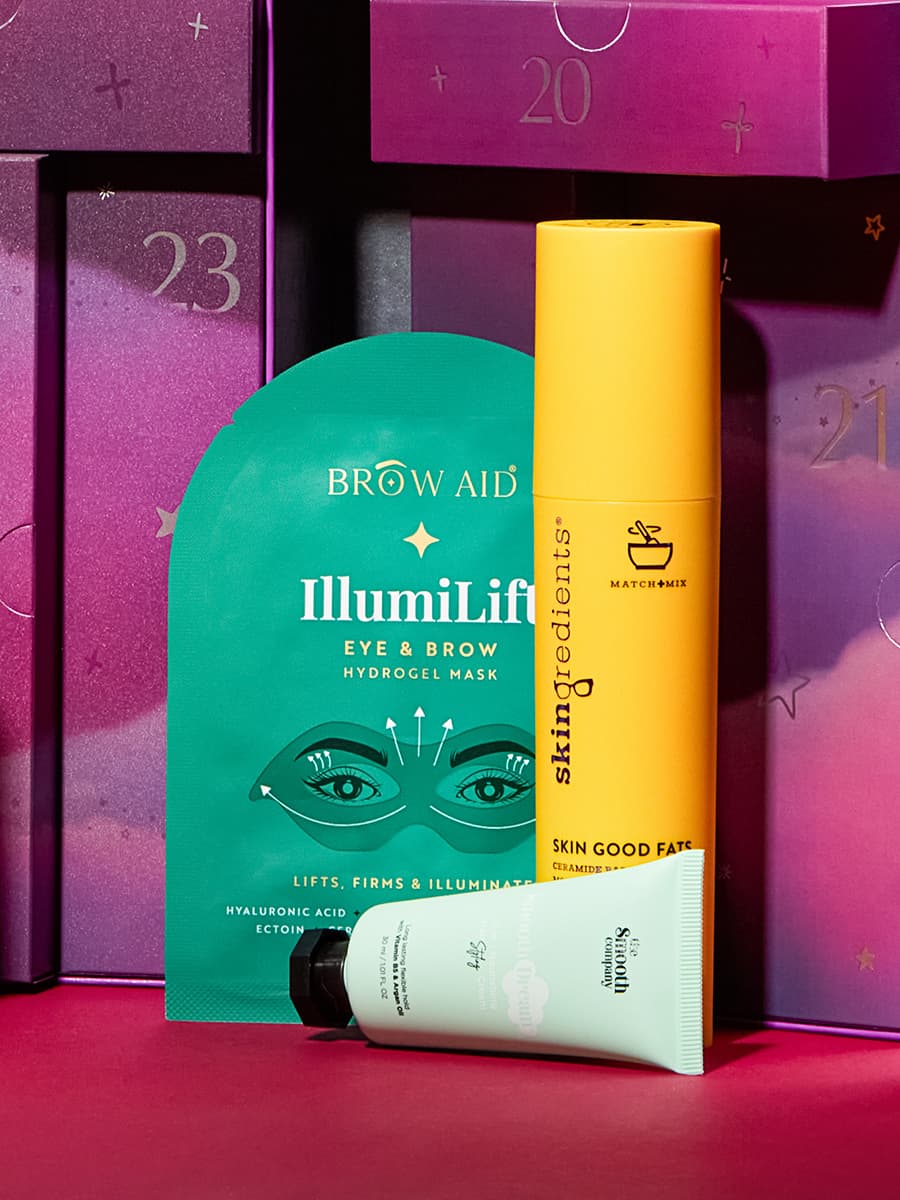 Beauty products including an eye and brow mask, a yellow cylindrical skincare tube, and a white tube, set against a purple background.