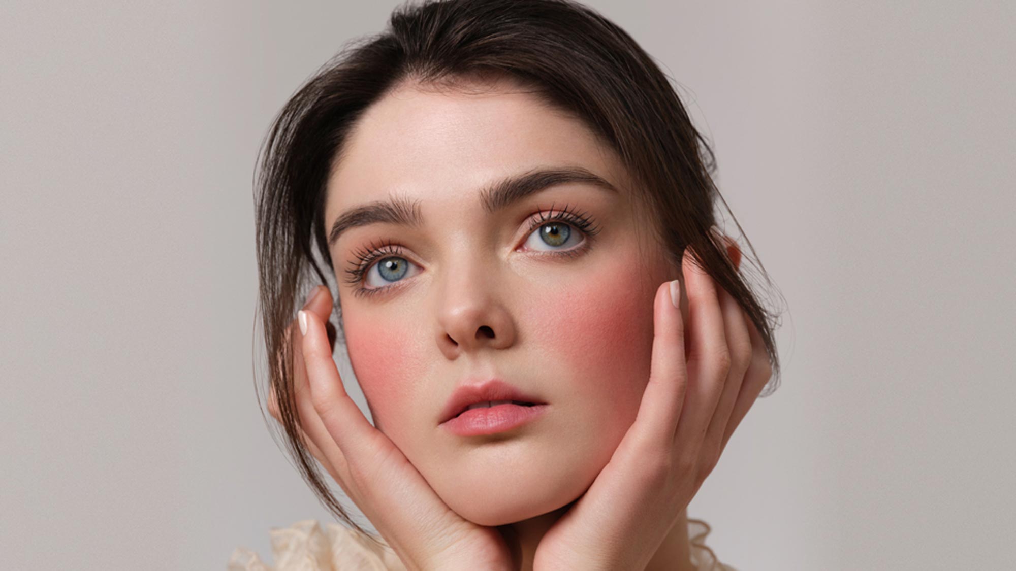 Woman with natural makeup featuring bronze eyeshadow, defined brows, and pink blush, demonstrating bridal beauty techniques