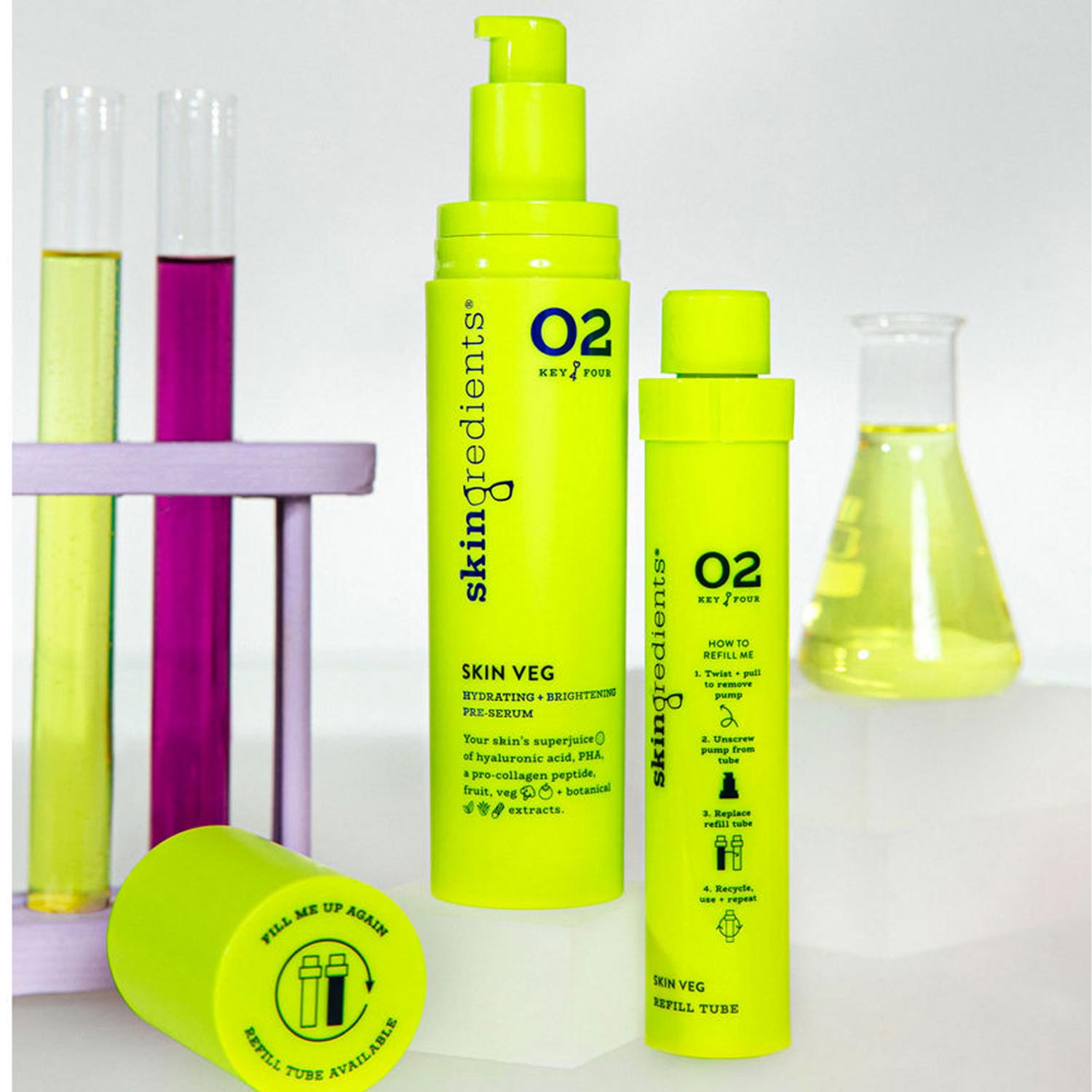 Bright green skincare bottles labeled 'Skingredients Skin Veg' with a pump and refill, surrounded by colorful test tubes and a beaker.