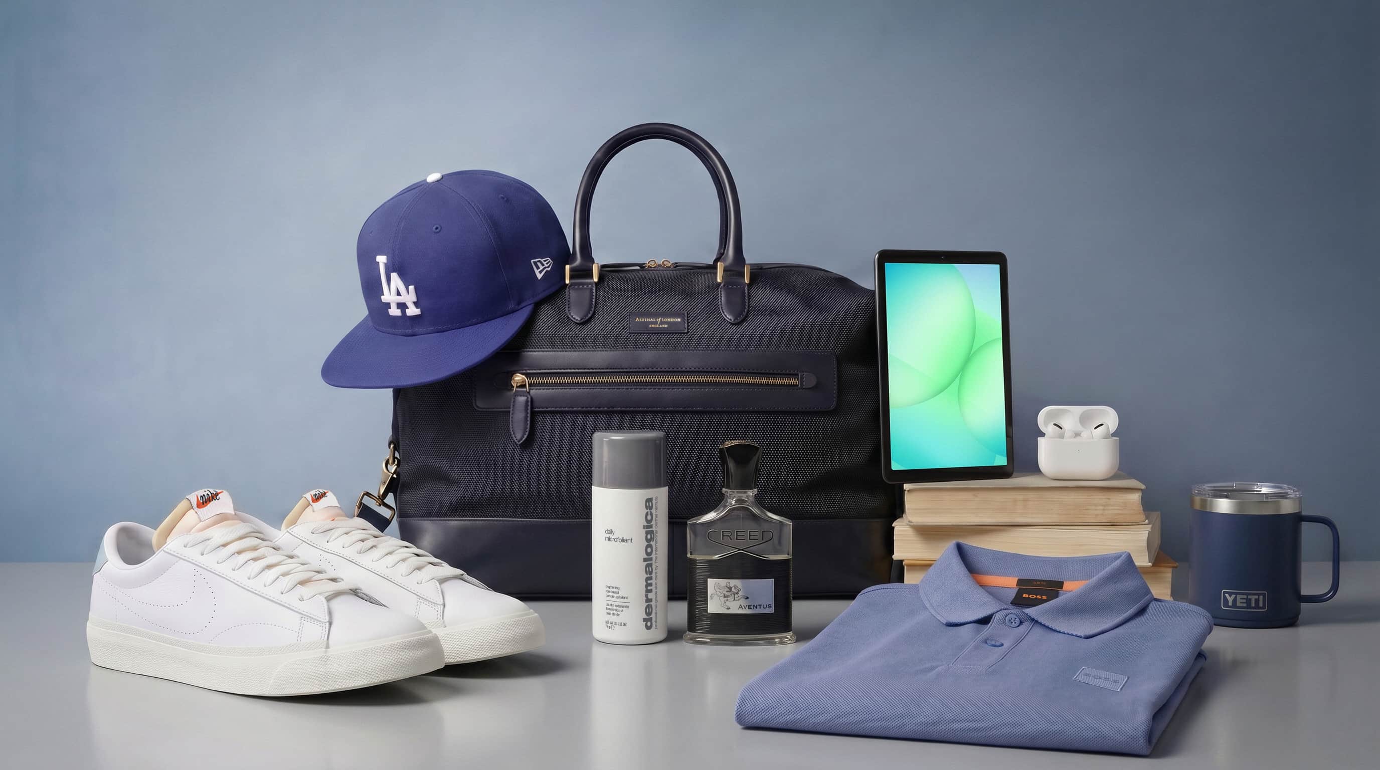 A selection of men's accessories including a bag, cap, shoes, polo shirt, tablet, cologne, AirPods, skincare item, and a mug displayed on a table.