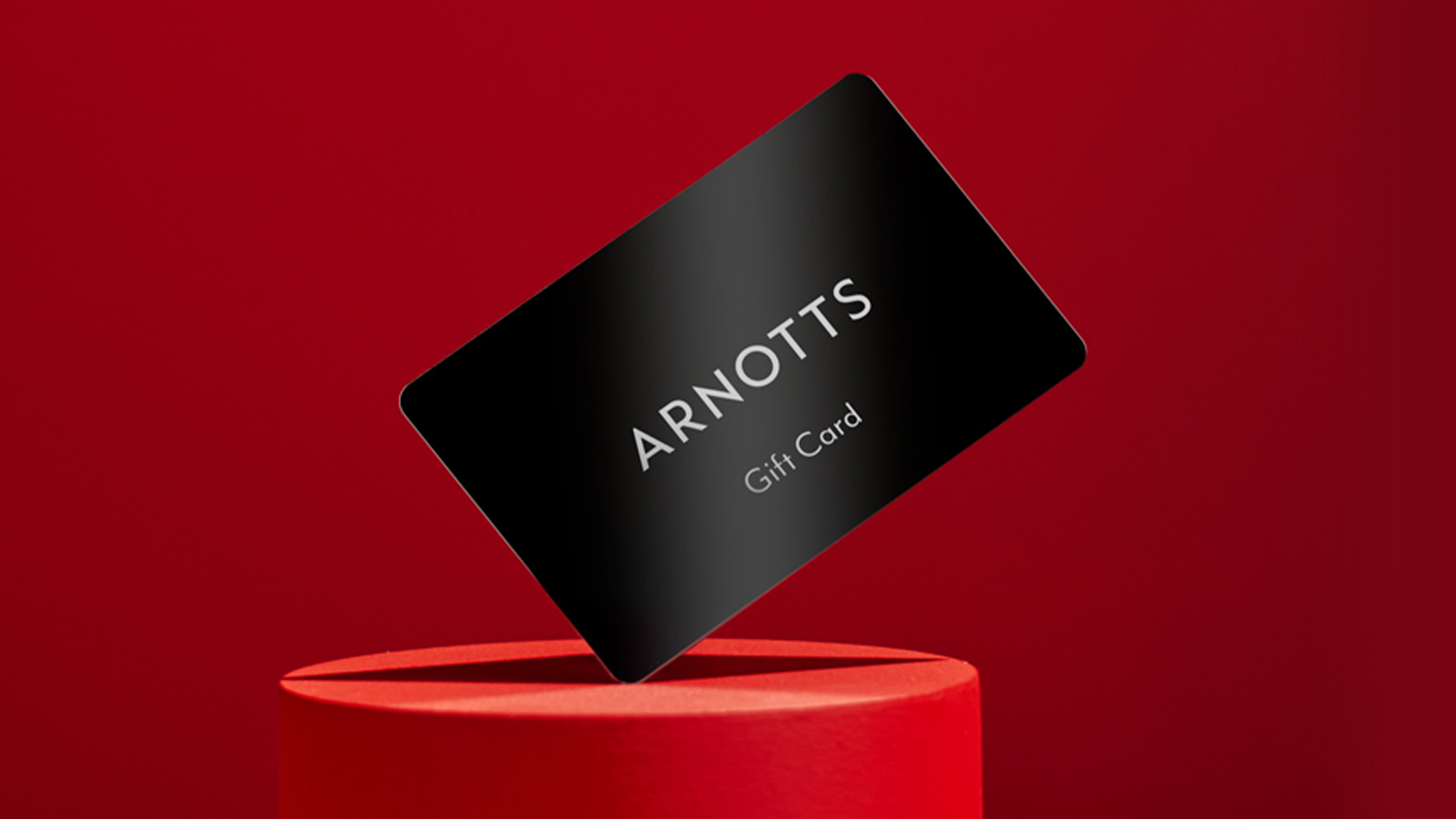 Red gift boxes with 'ARNOTTS' branding, a smartphone displaying a screen, and a small black ribbon-wrapped box on a blue background.
