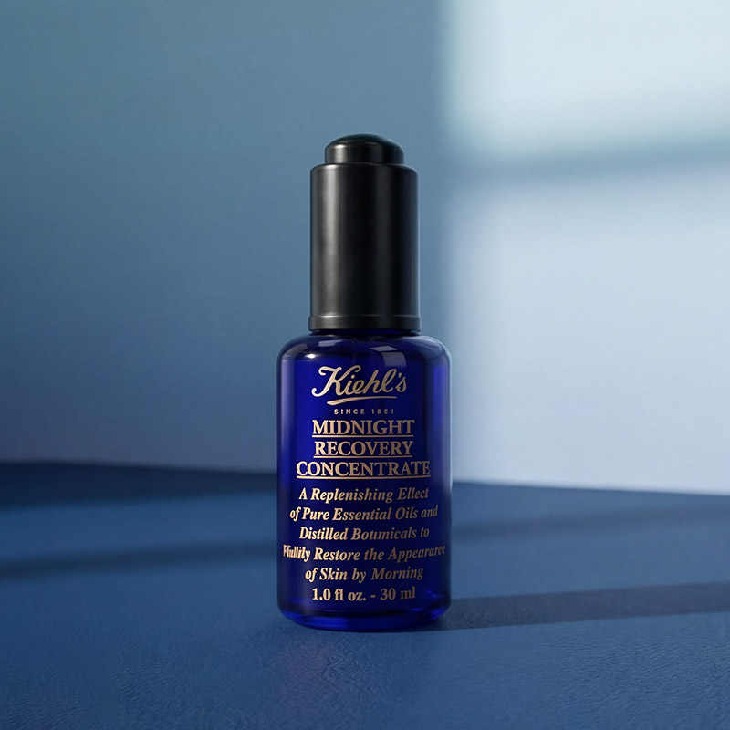 A blue bottle of Kiehl's Midnight Recovery Concentrate placed against a soft, gradient background.