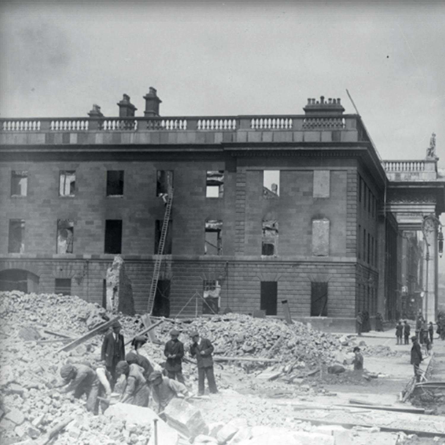 Black and white photograph of a damaged stone building with broken windows and rubble in foreground during Easter Rising reconstruction