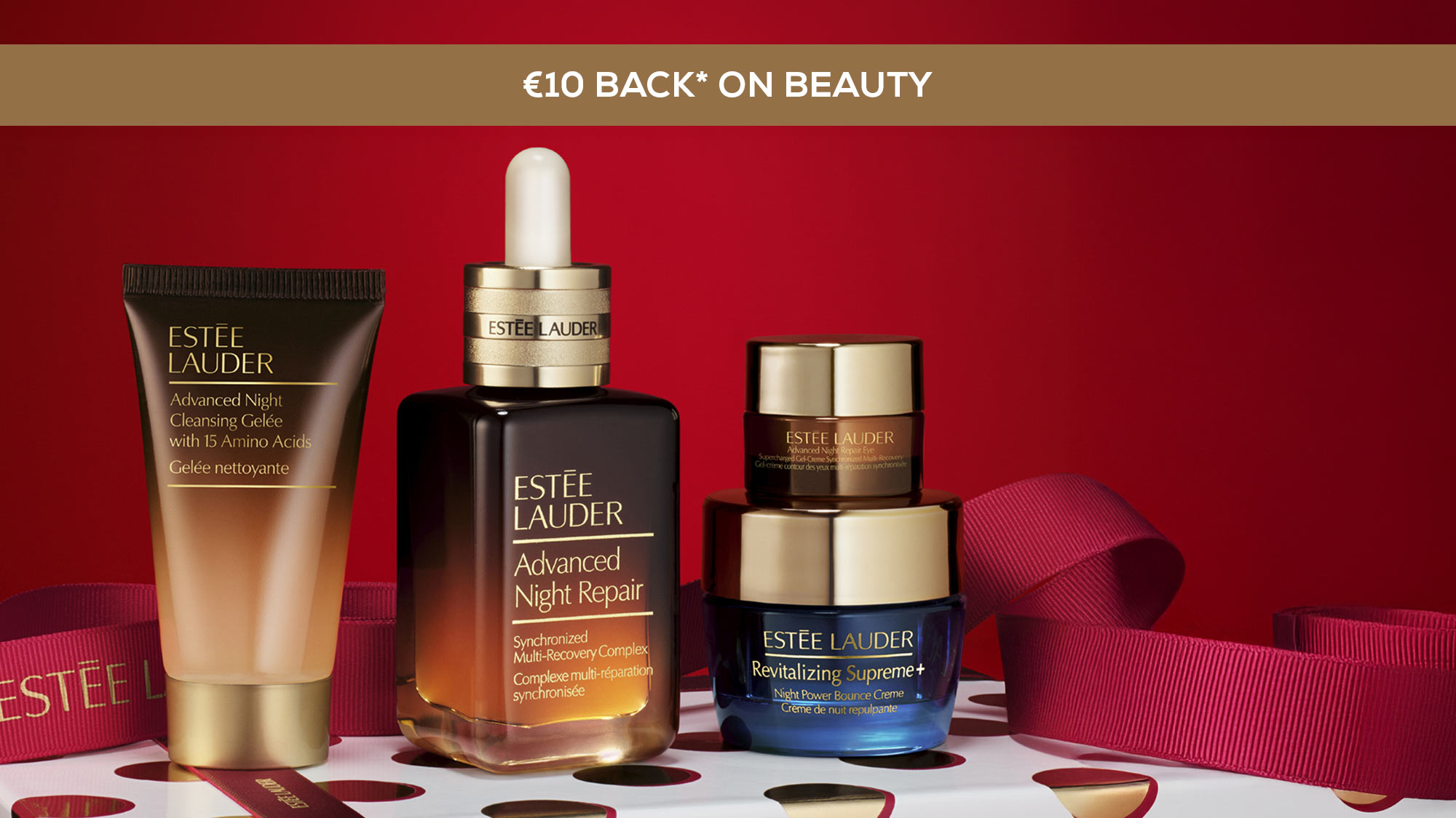 Estee Lauder skincare products displayed on a polka dot gift box with a red background.