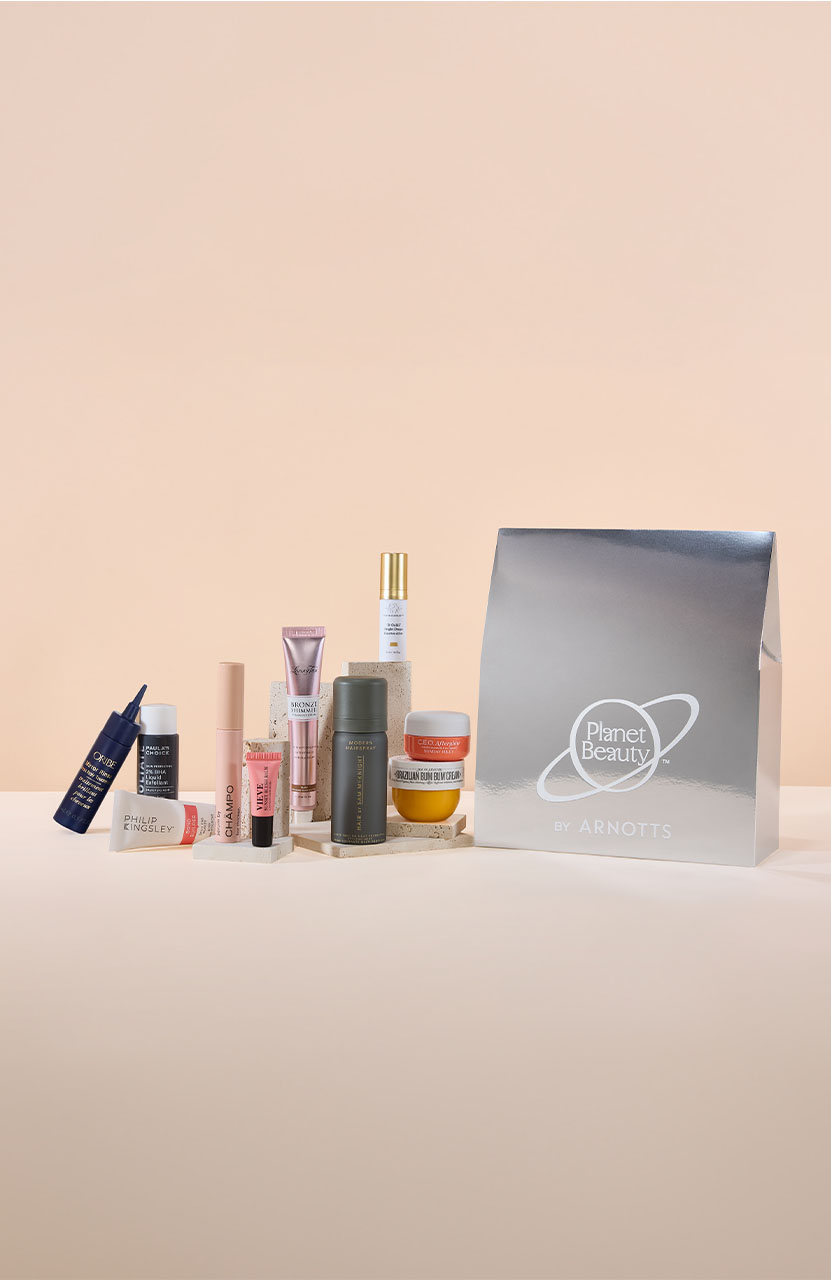 A collection of beauty products arranged next to a silver 'Planet Beauty by Arnotts' gift bag.