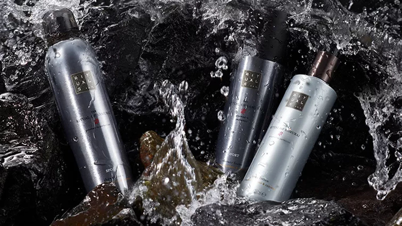 
Three bottles of Rituals products are surrounded by splashing water and rocks, creating a refreshing and dynamic scene.

