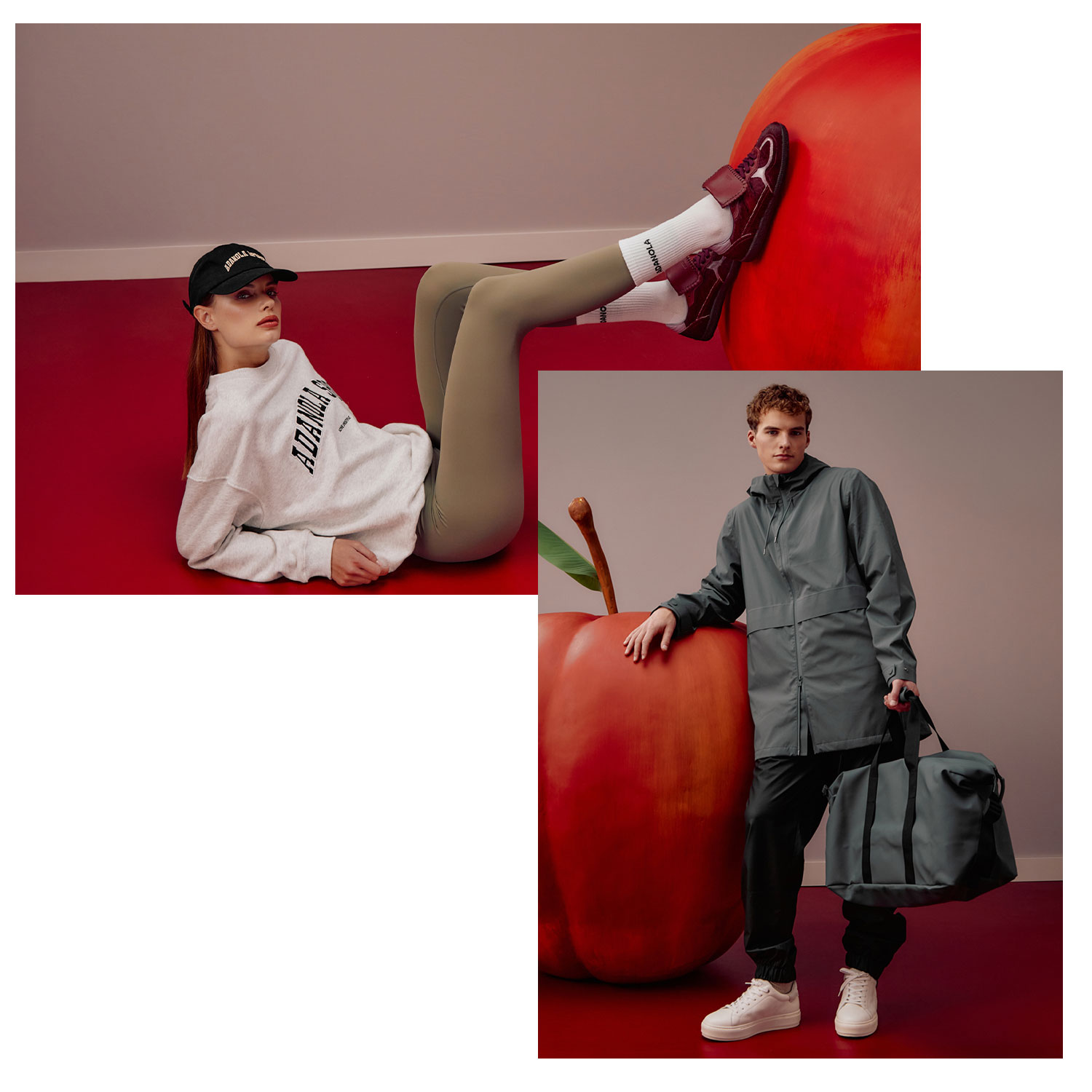 Two people in casual outfits pose with oversized red apples in a minimalist setting.