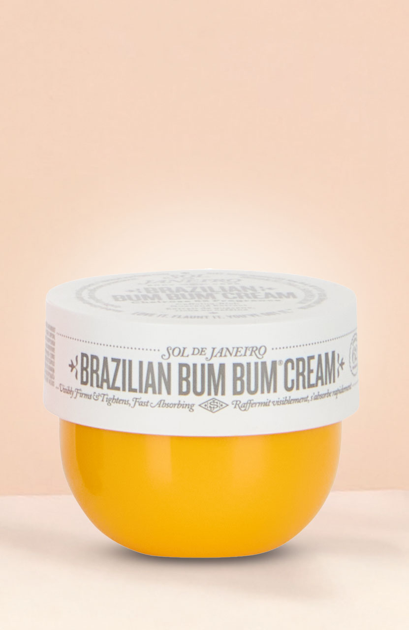 A yellow container of 'Brazilian Bum Bum Cream' with a white lid against a light pink background.