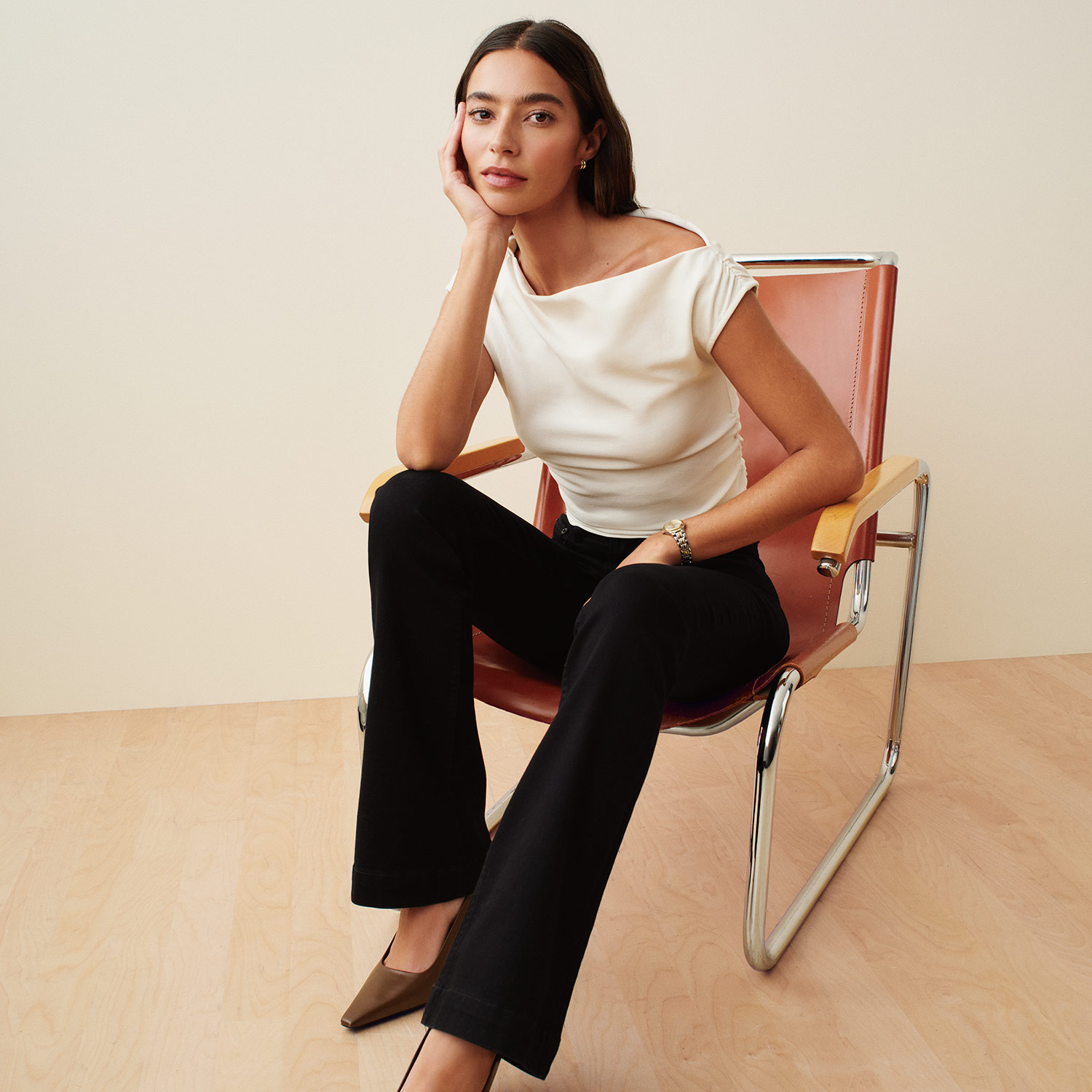 A woman in a black shaping bodysuit with thin straps poses confidently against a neutral background.