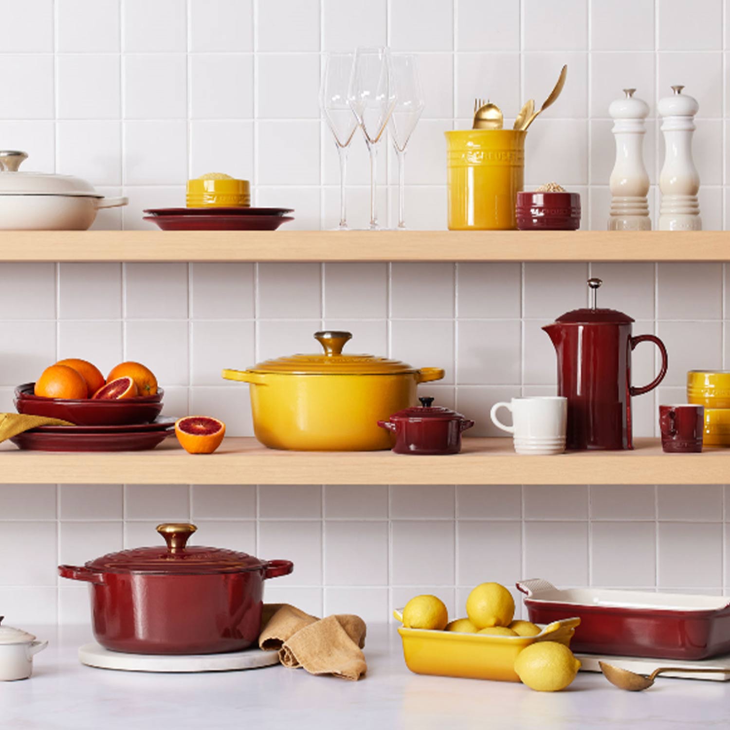 le creuset red and yellow and orange bakeware and cookware stacked on shelves