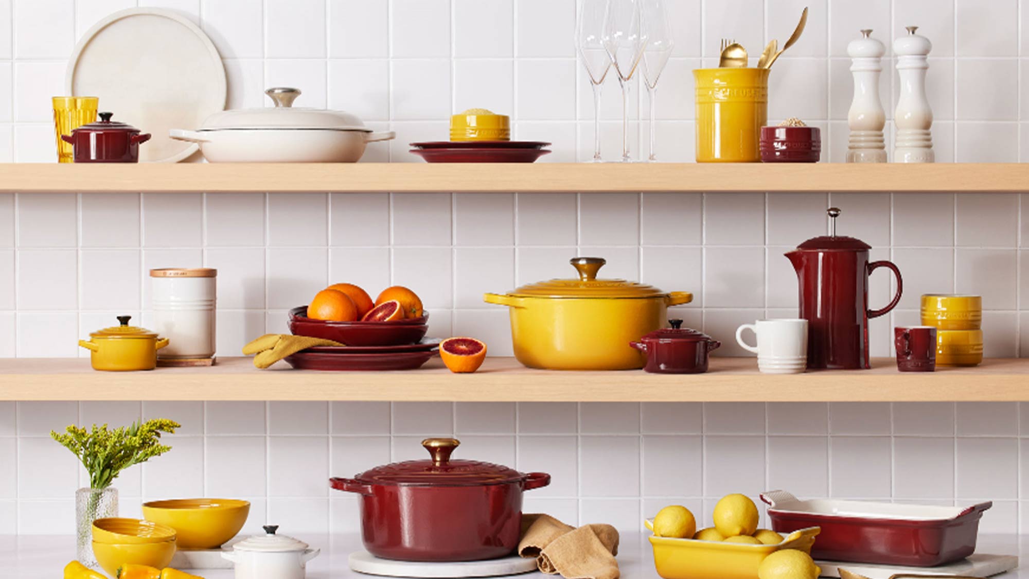 le creuset red and yellow and orange bakeware and cookware stacked on shelves