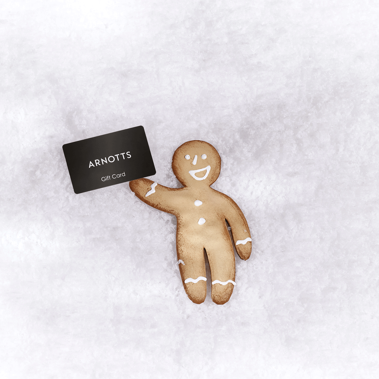 A gingerbread man holding an 'Arnotts Gift Card' on a snowy background.