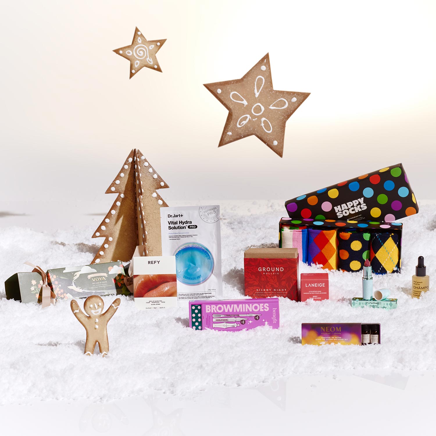 A festive display of assorted gift items, including skincare, socks, and a gingerbread figure, set against a snowy background with star decorations.