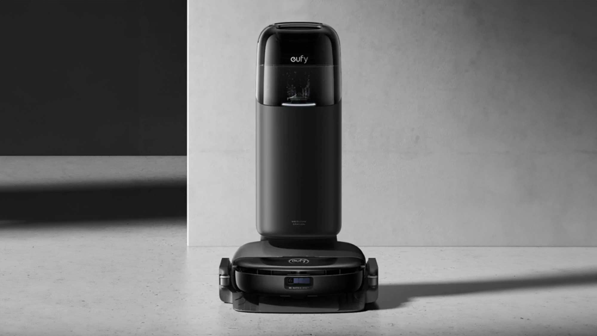 A sleek, black robotic vacuum cleaner with its charging and dust disposal station on a minimalist gray surface.