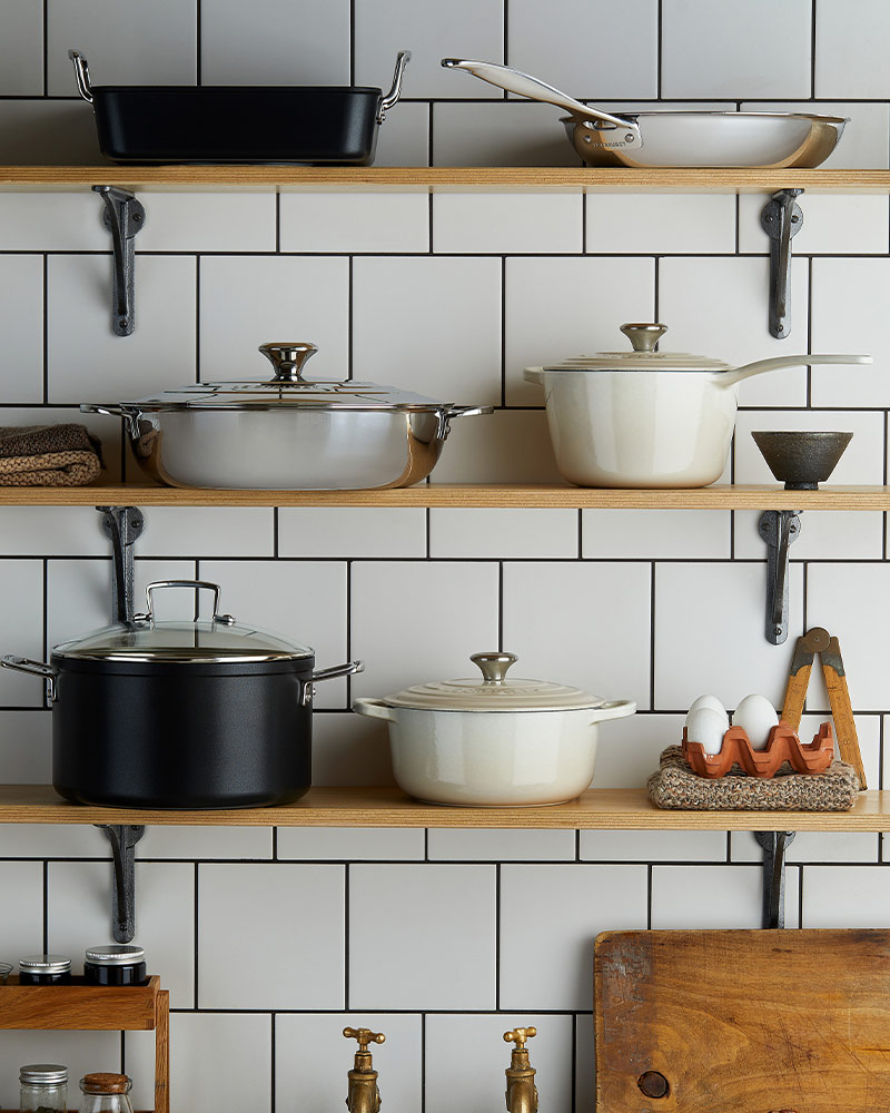 Kitchen shelves with pots, pans, and eggs on a tiled wall background.