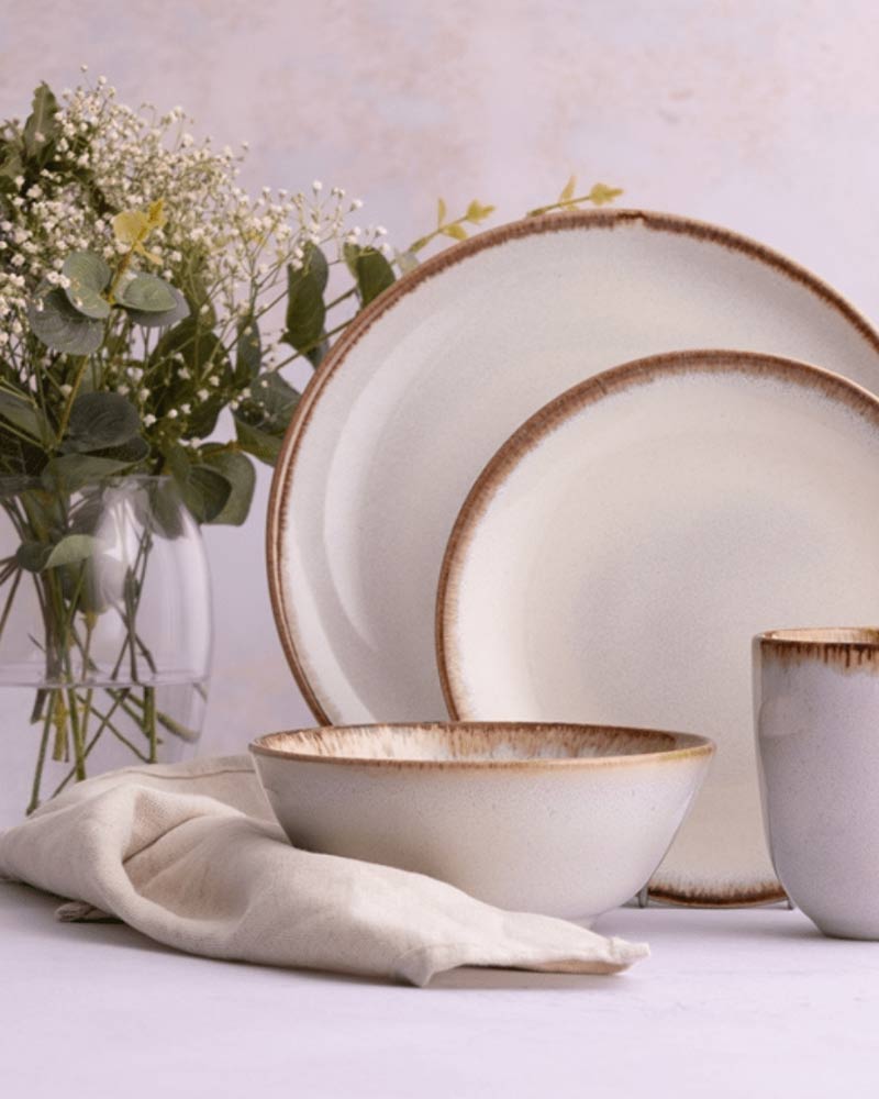 Elegant table setting with a white bowl, green glassware, and a light green napkin on a textured surface.