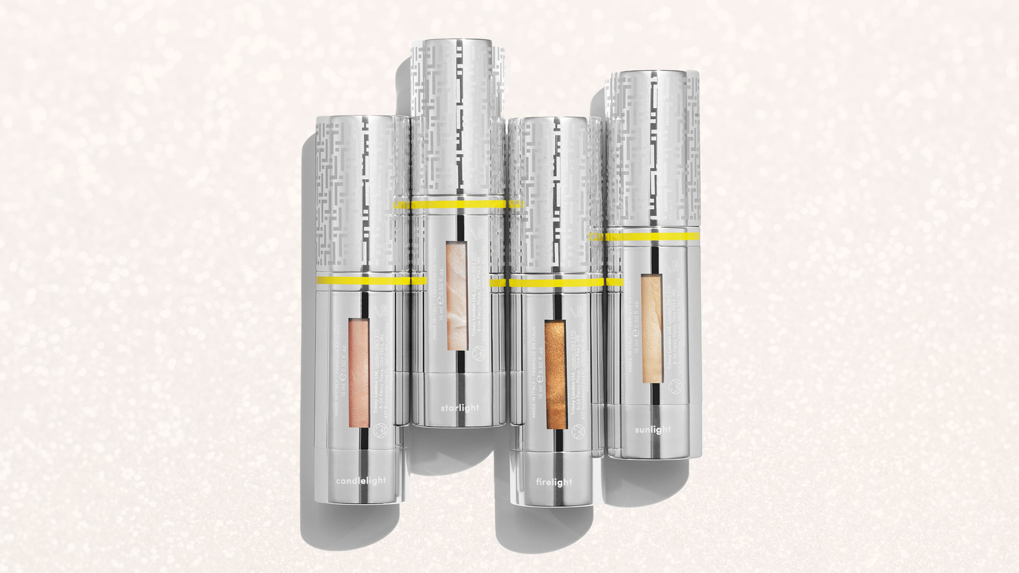 Four metallic cylindrical containers with transparent sections reveal different shades of cream inside.