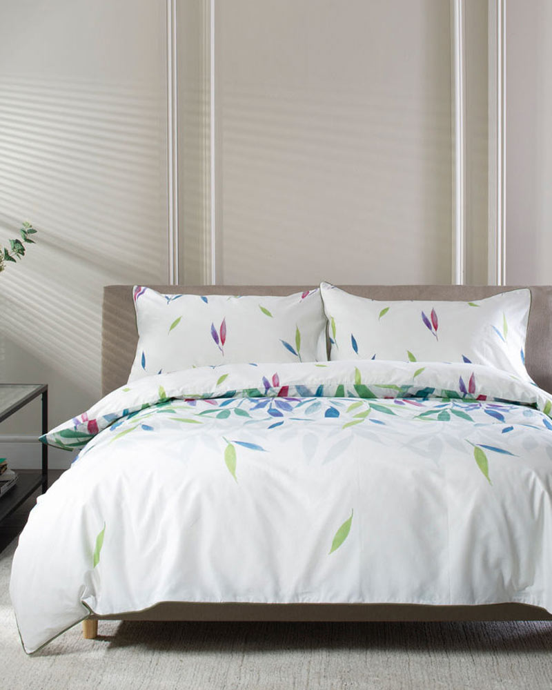 A neatly made bed with a white duvet cover featuring colorful leaf patterns.
