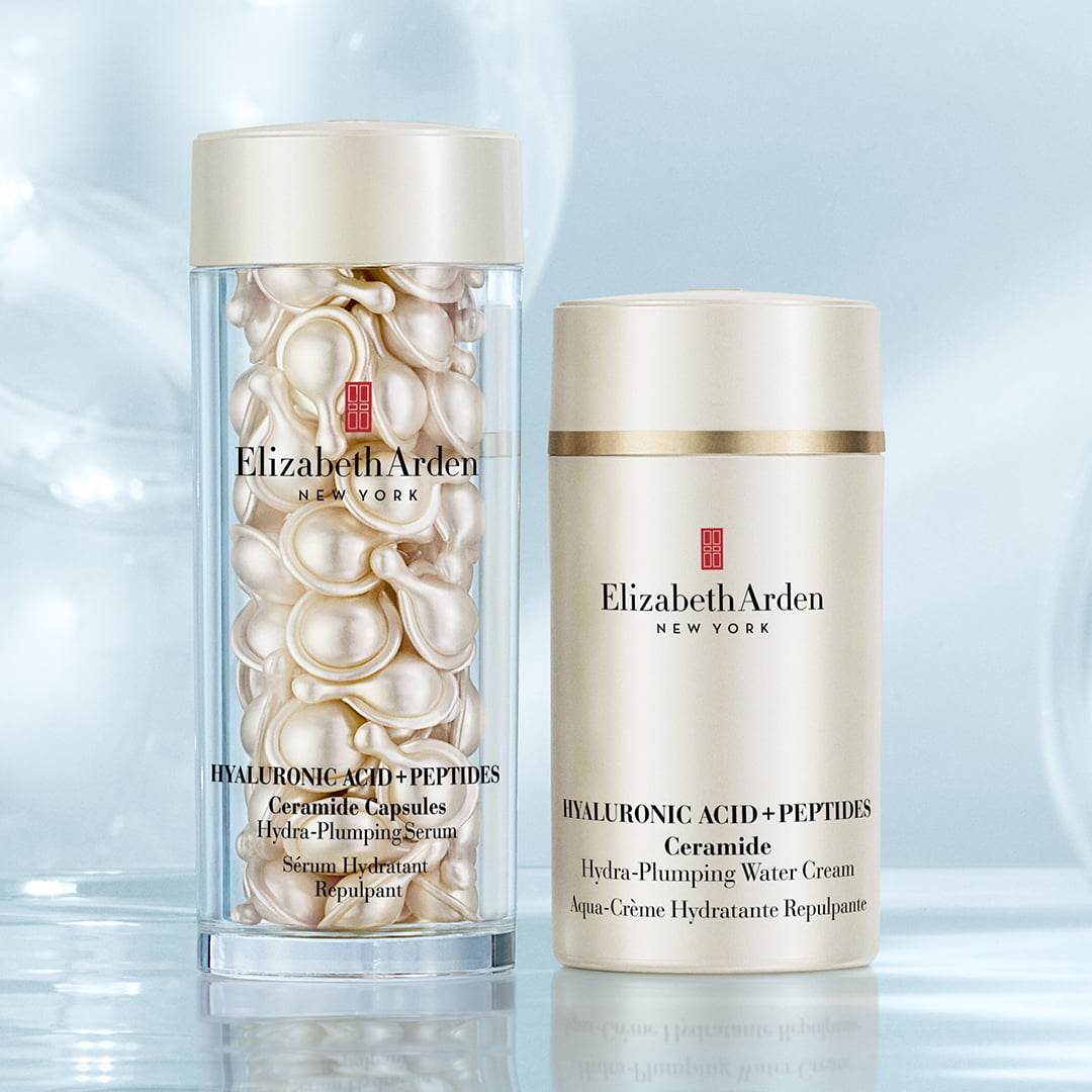 Two Elizabeth Arden skincare products with ceramide capsules and moisturizing cream on a reflective surface, surrounded by soft-focus bubbles.