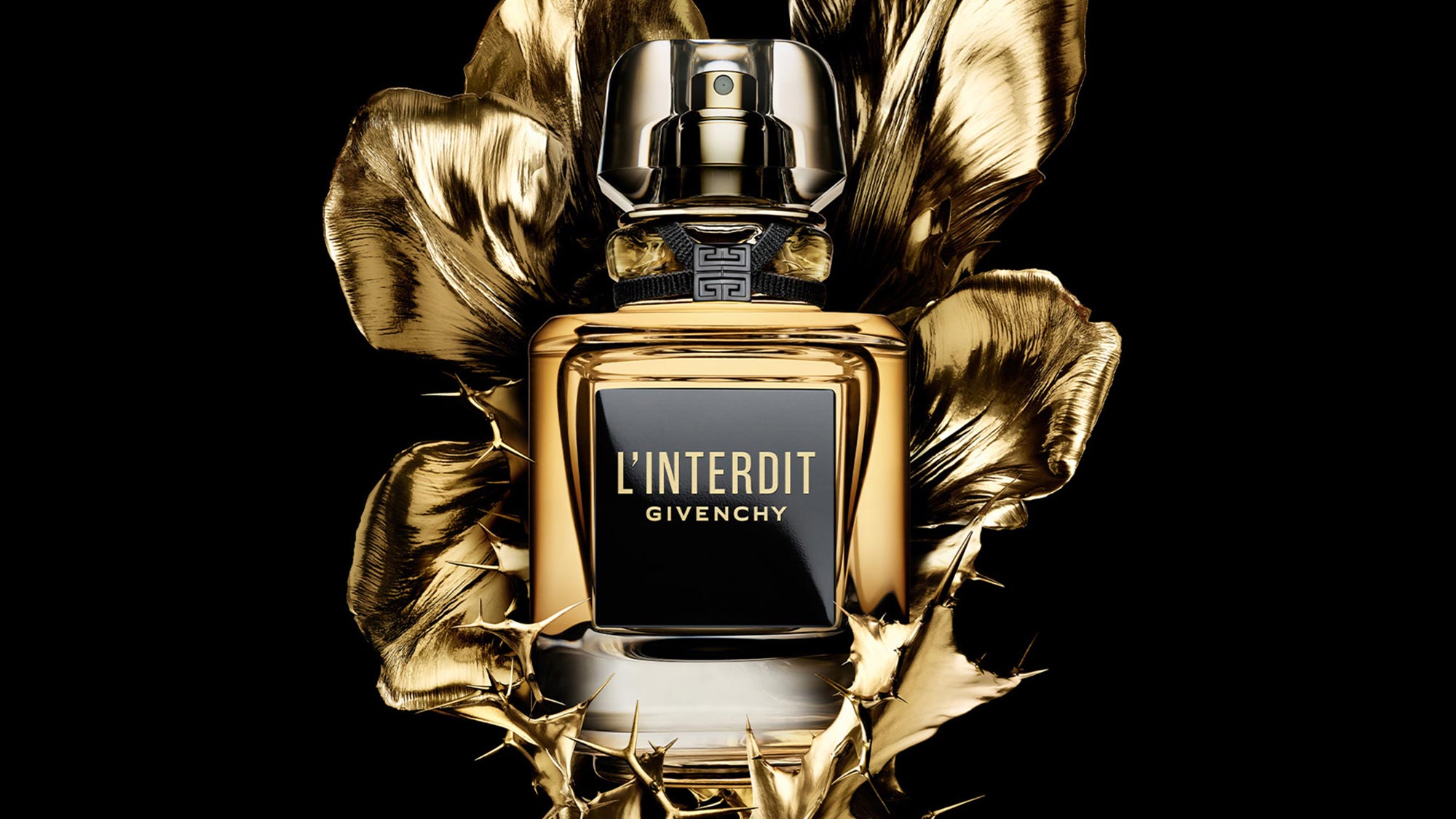 A bottle of L'Interdit Givenchy perfume is surrounded by gold floral accents against a black background.