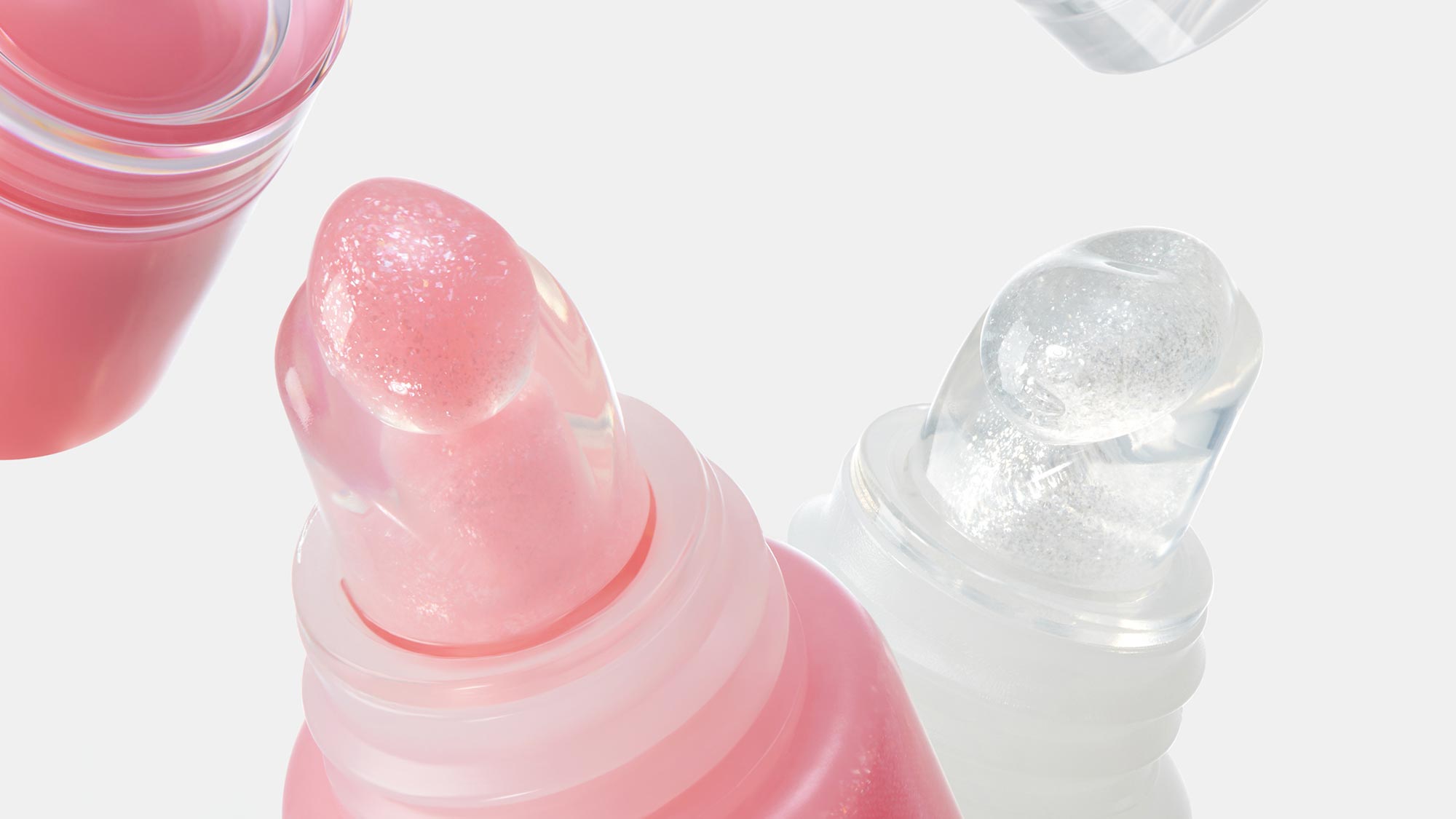 Close-up of translucent pink and clear lipstick and lip balm tubes against a white background.