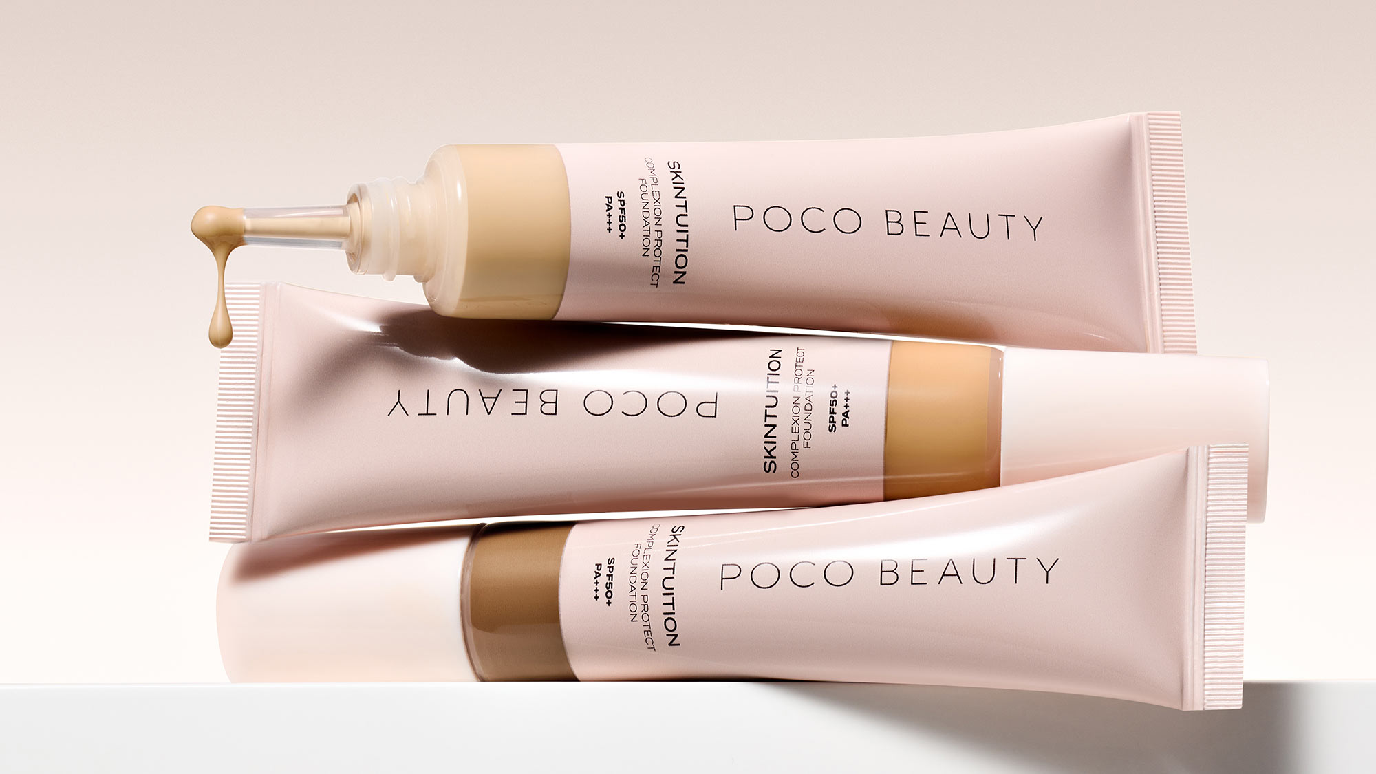 Three tubes of Poco Beauty foundation arranged neatly, with one pumping out liquid.