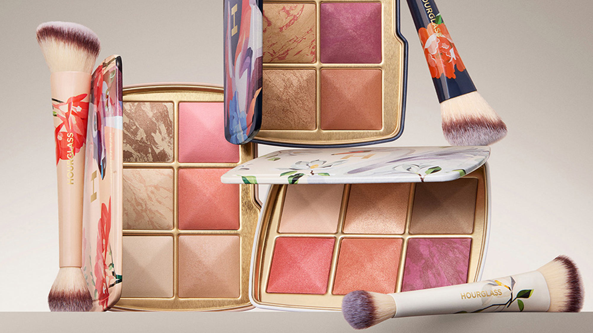 Makeup palettes with multi-colored powders and floral designs, accompanied by two brushes.