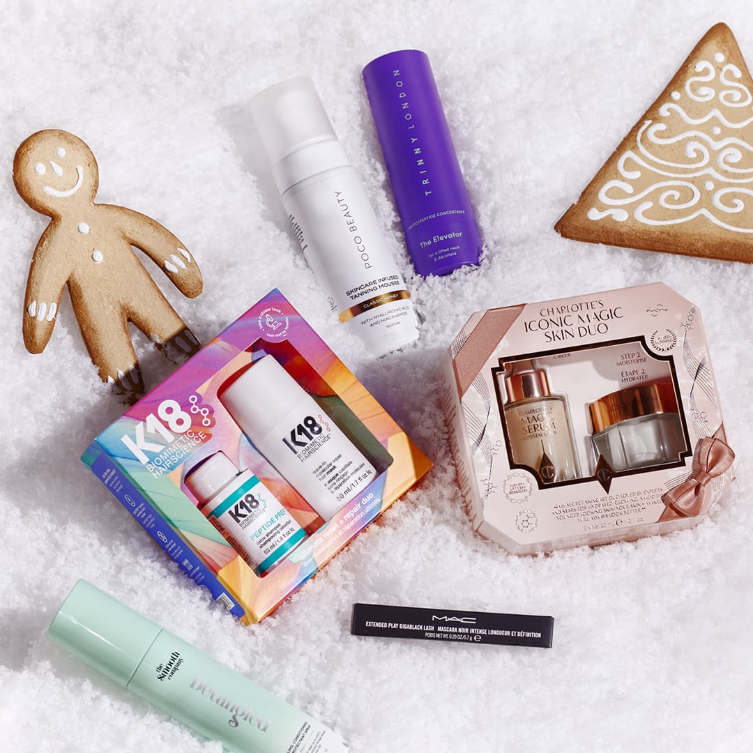 Beauty products displayed on a snowy surface with gingerbread cookies around.